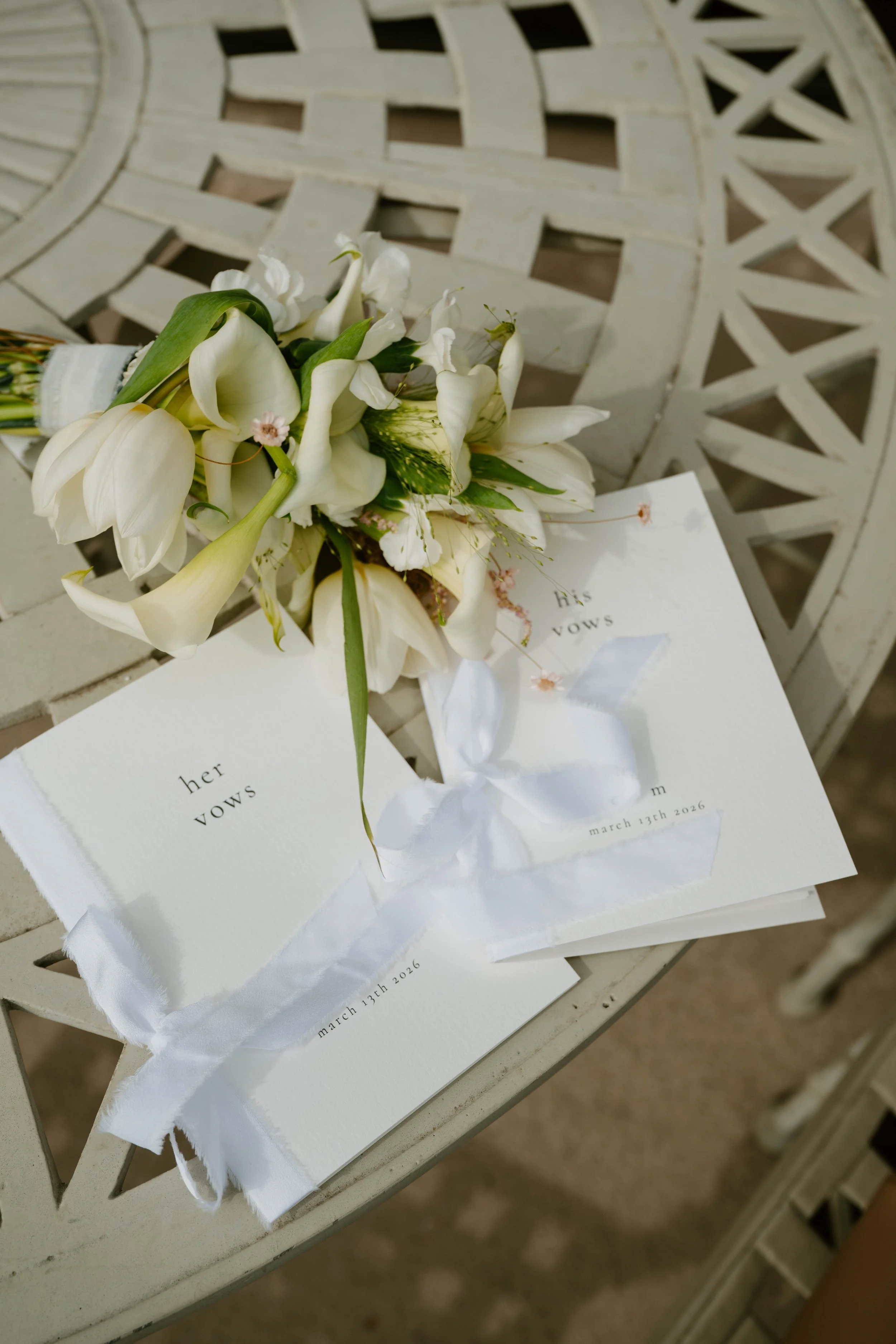 close up photo of wedding bouquet and his & her vow books