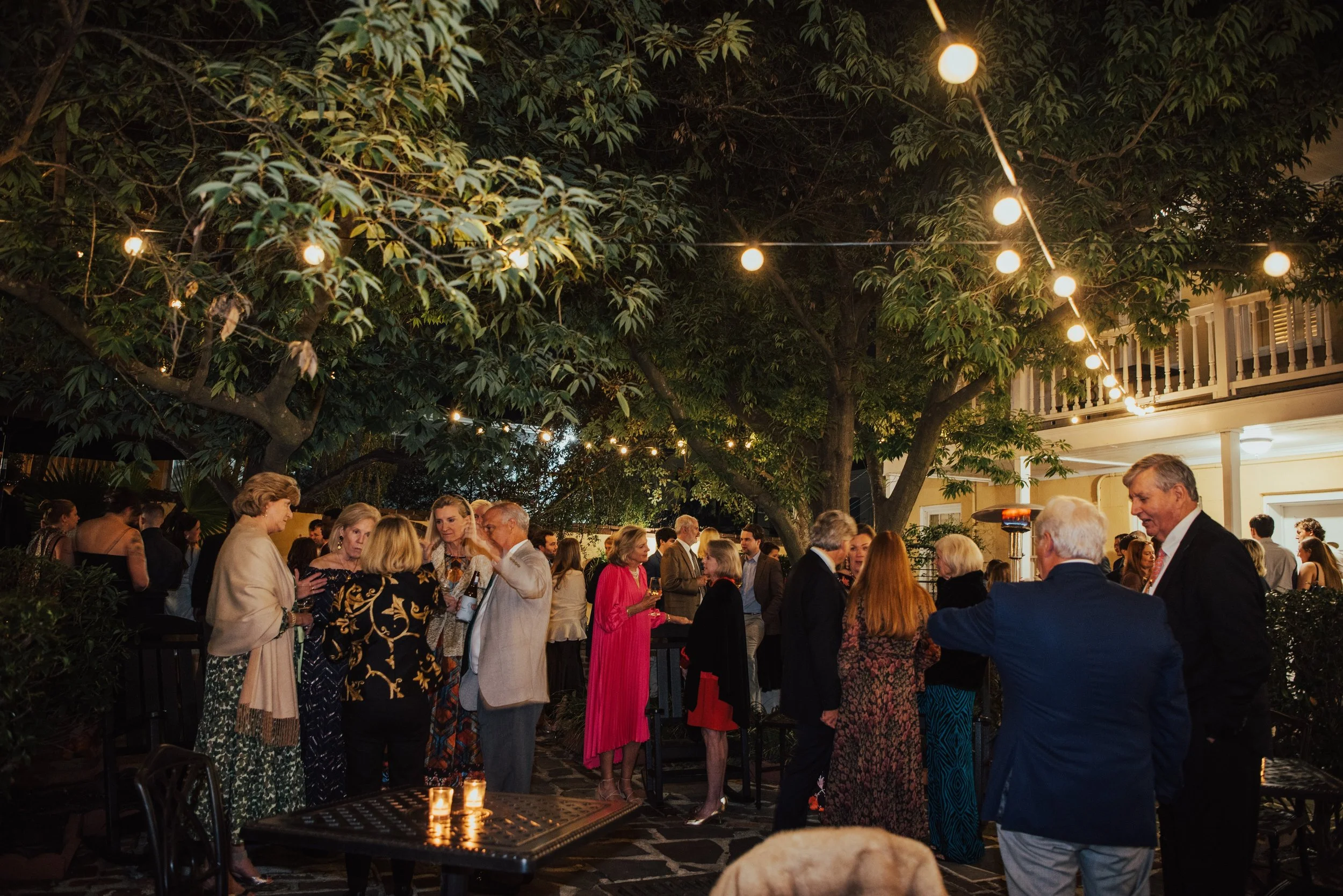 Wedding guest standing in a courtyard at night under bistro lights for a wedding Welcome party.