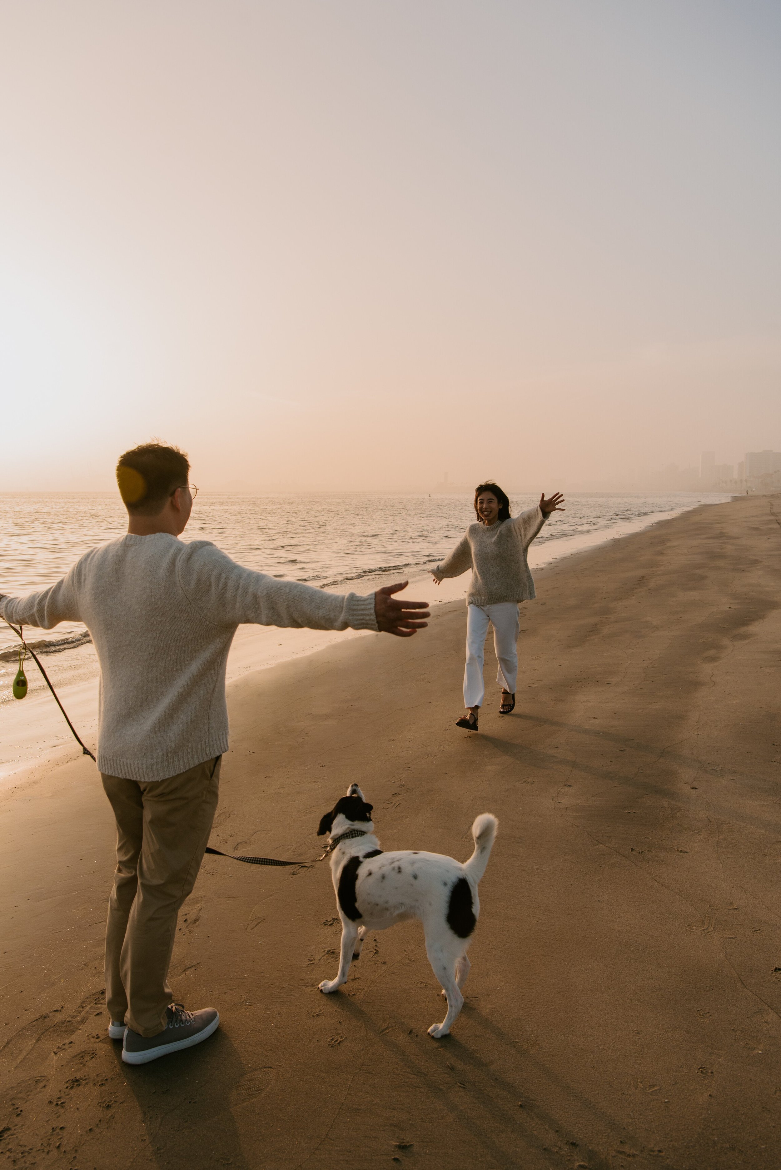 Girl running toward guys and dog with arms wide