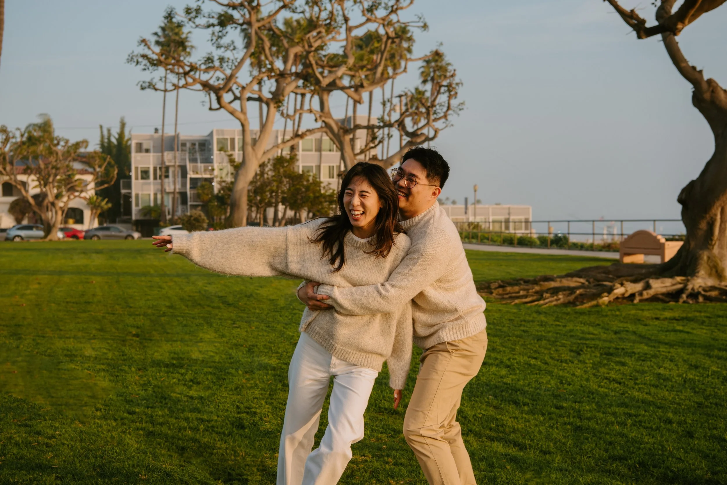 Couple laughing as guys hugs girl from the side