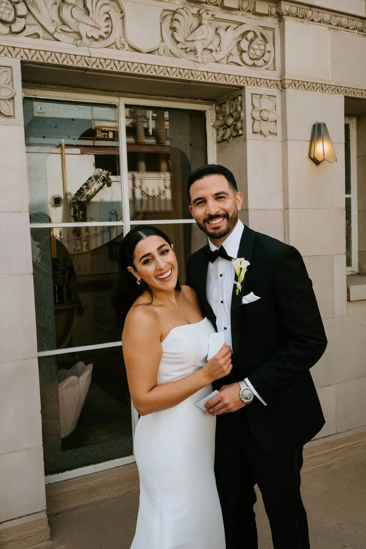 Bride and groom smiling and looking at the camera out on the balcony of penthouse
