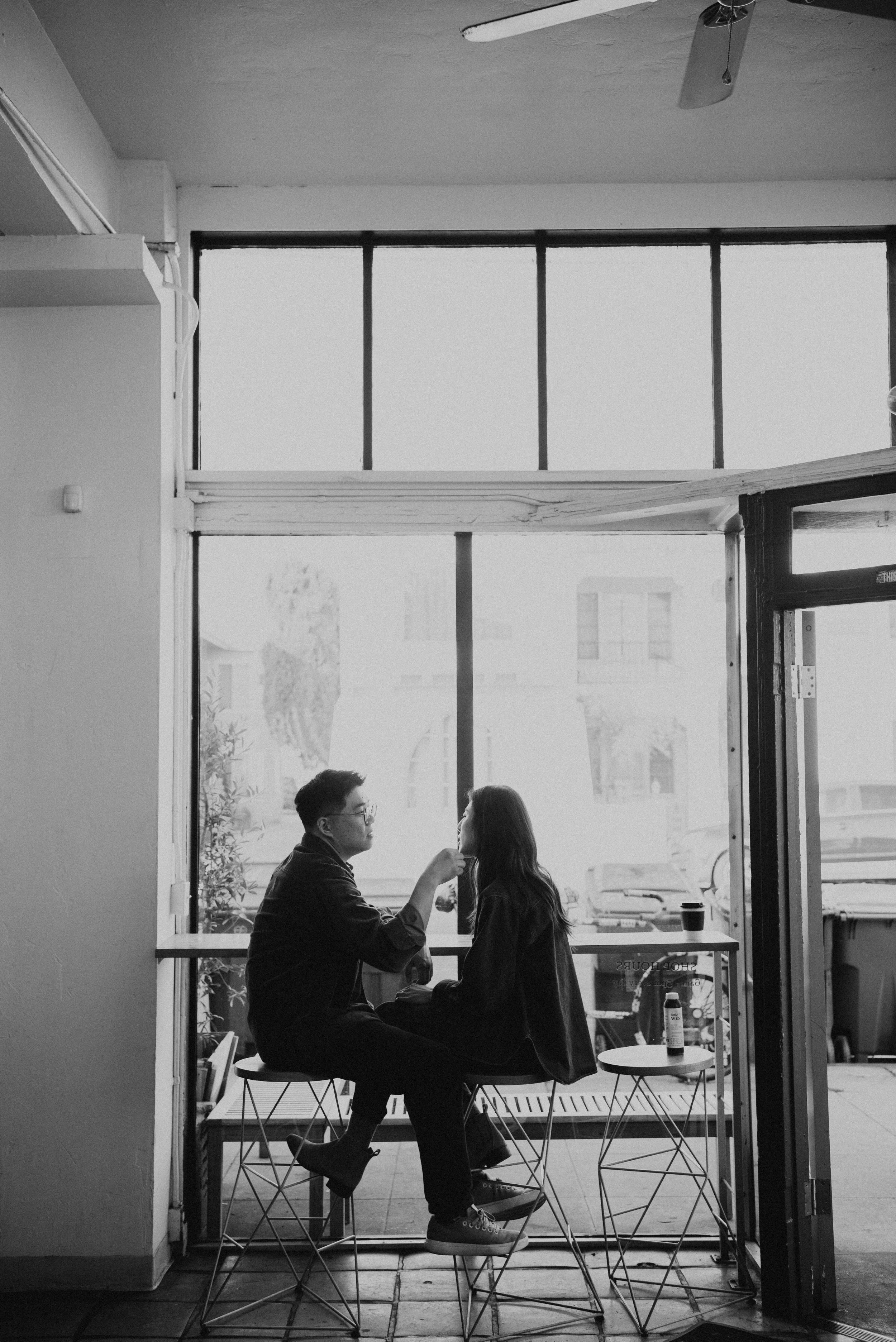 Black and white photo of couple sitting at window seats in a coffee shop