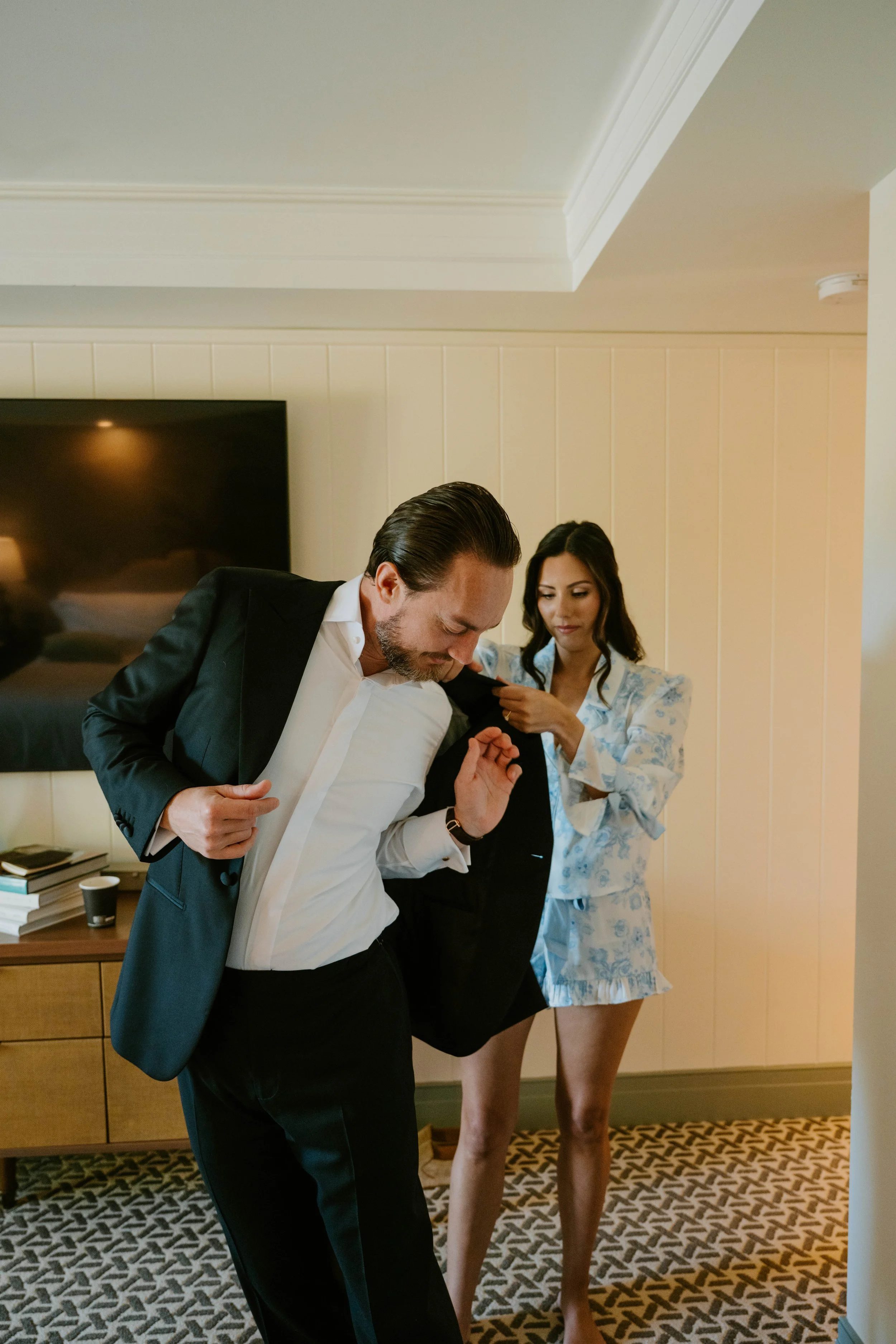 Bride in PJ set helping groom put on his jacket