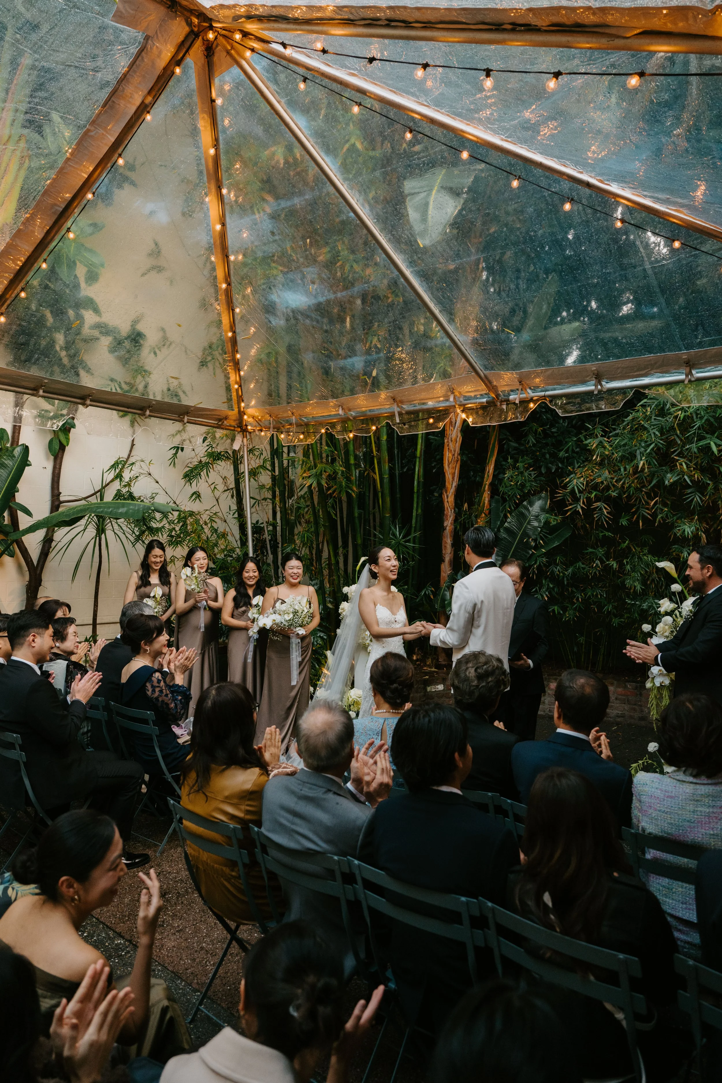 shot from the side showing the bride laughing as she hold hands with the groom during their ceremony