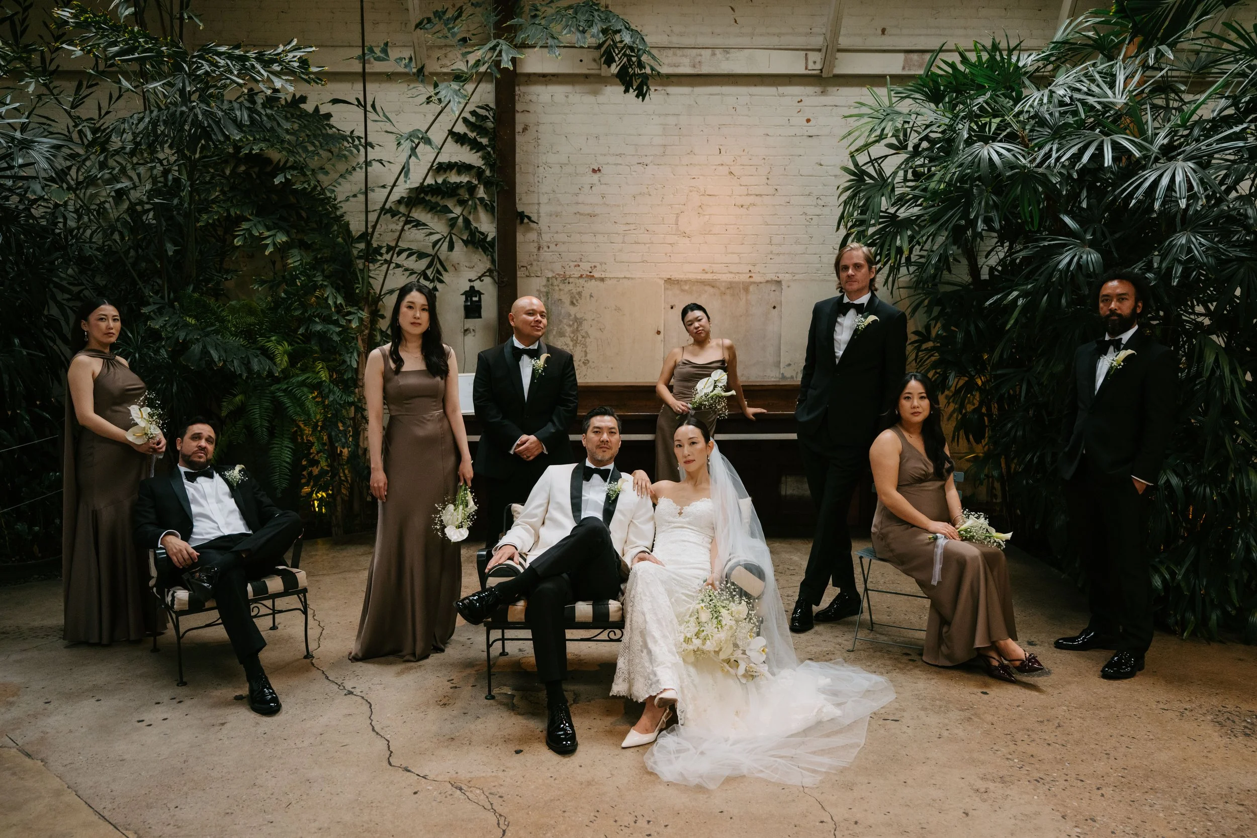 Bride and groom sitting in the front with their wedding party around them. Some of them are sitting and some are standing to give the photo different levels