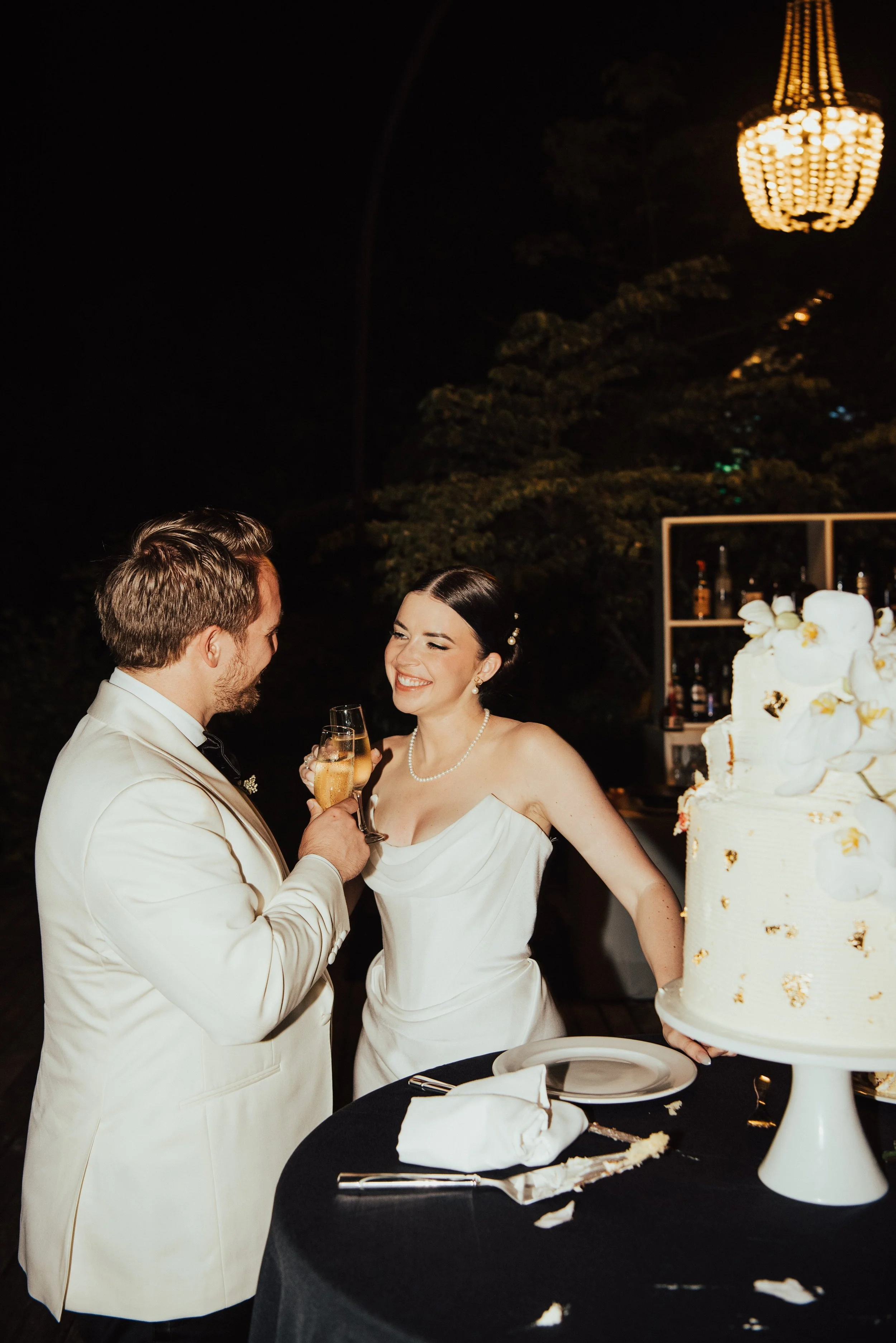 Bride and groom smiling as they clink glasses together
