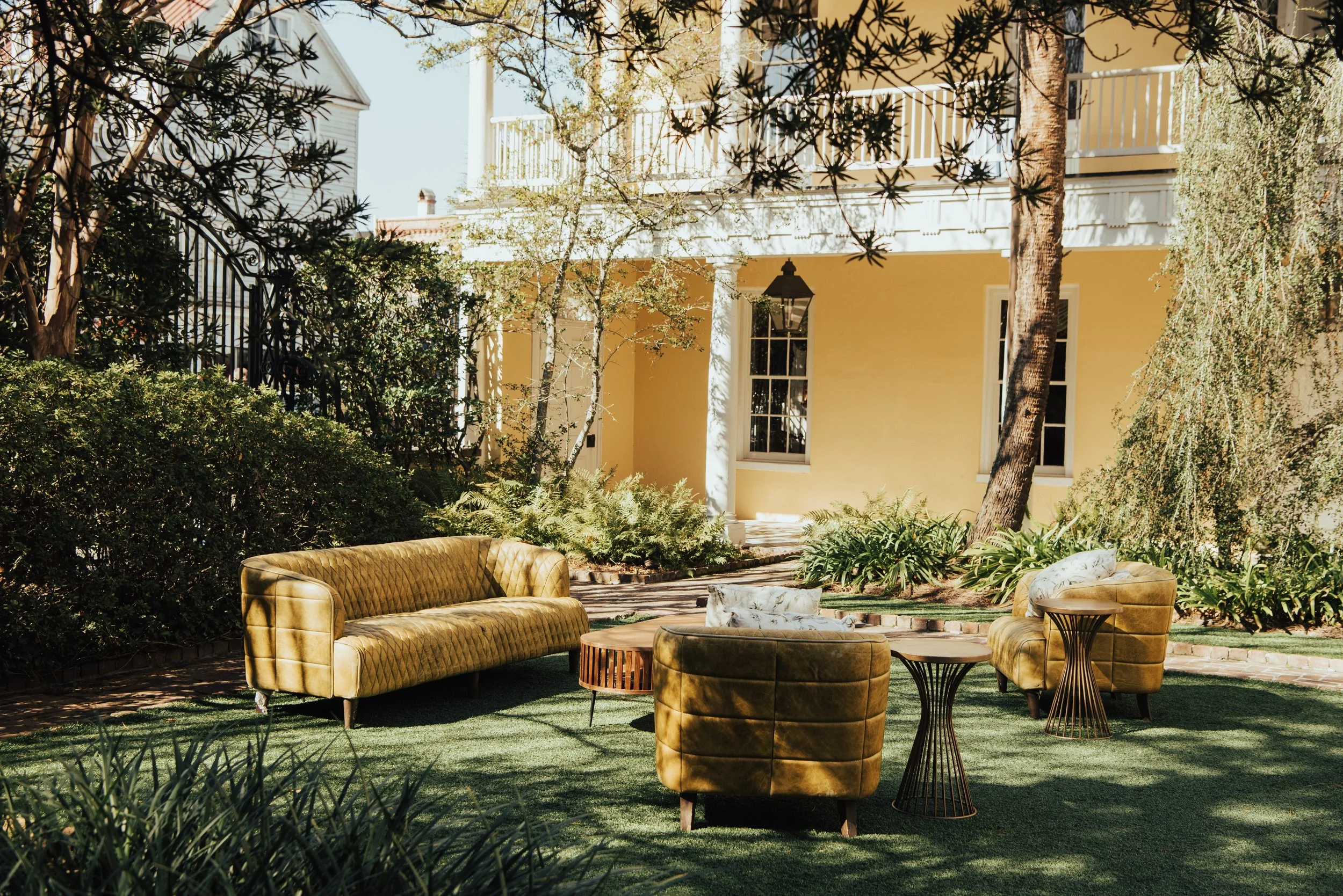 Photo of a greenish lounge set on a lawn, in front of a Yellow house