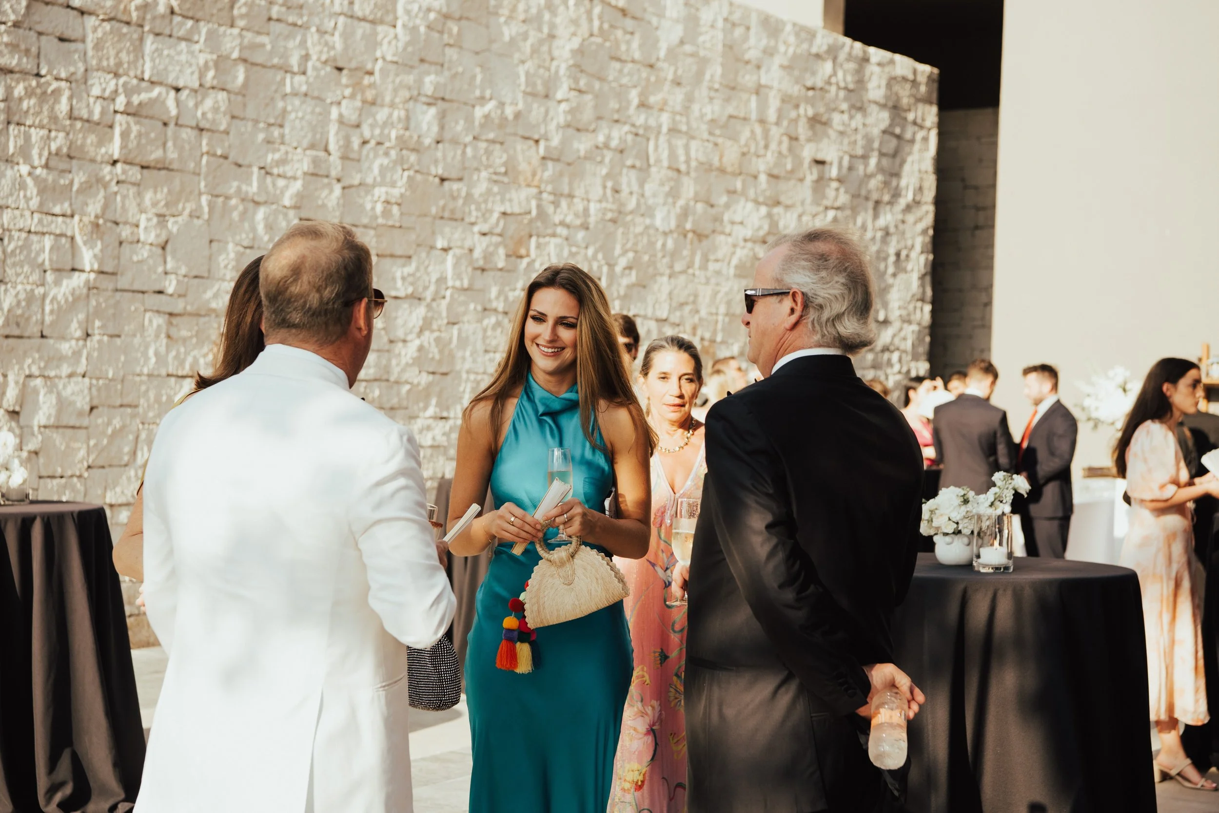 Woman in blue dress smiling as she greets other guests.
