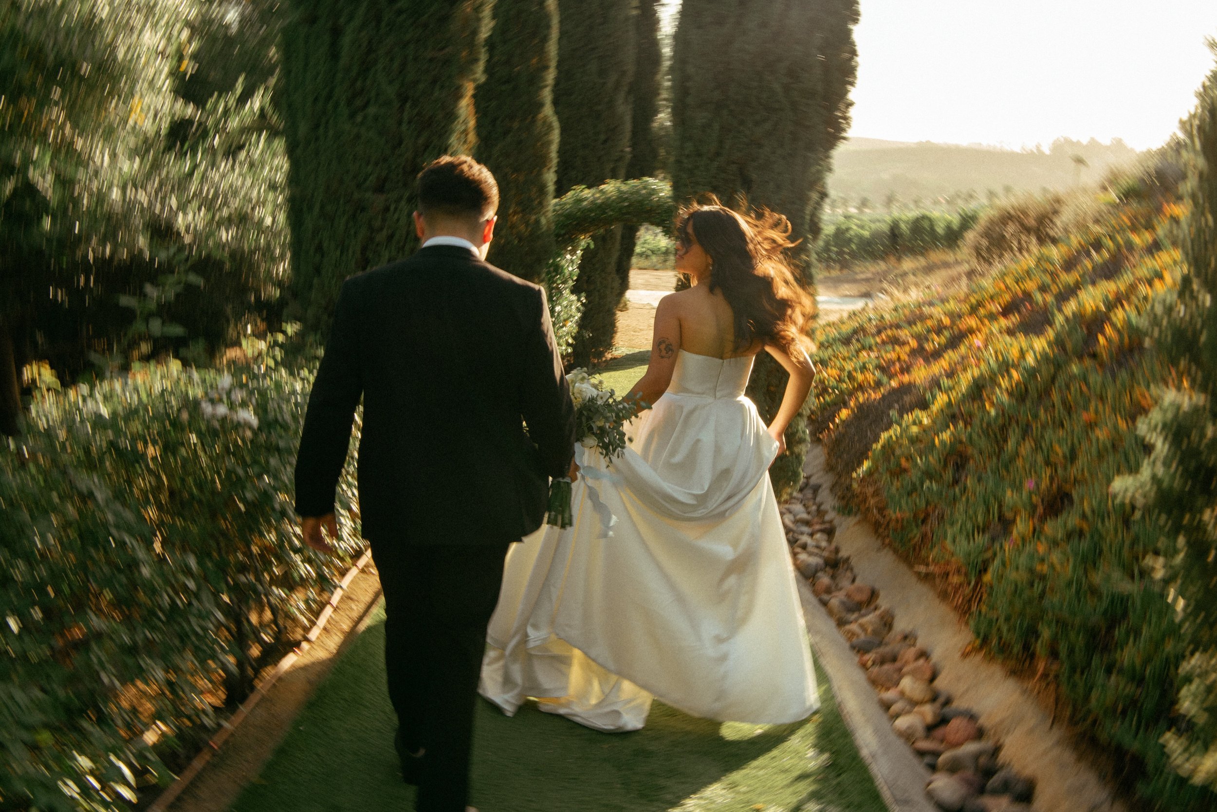 Bride and groom walking away from the camera at a winery during golden hour
