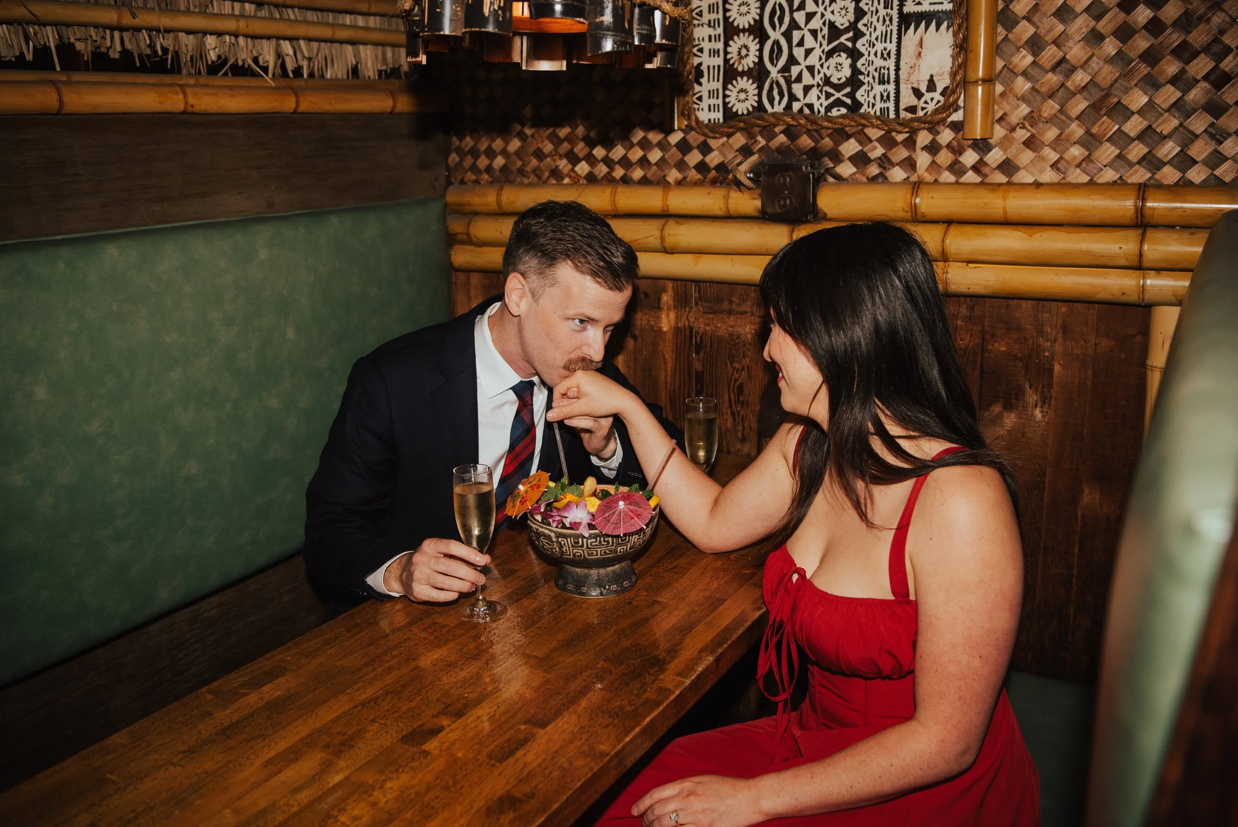 Couple sitting across a table front each other. Guys is kissing woman’s s hand
