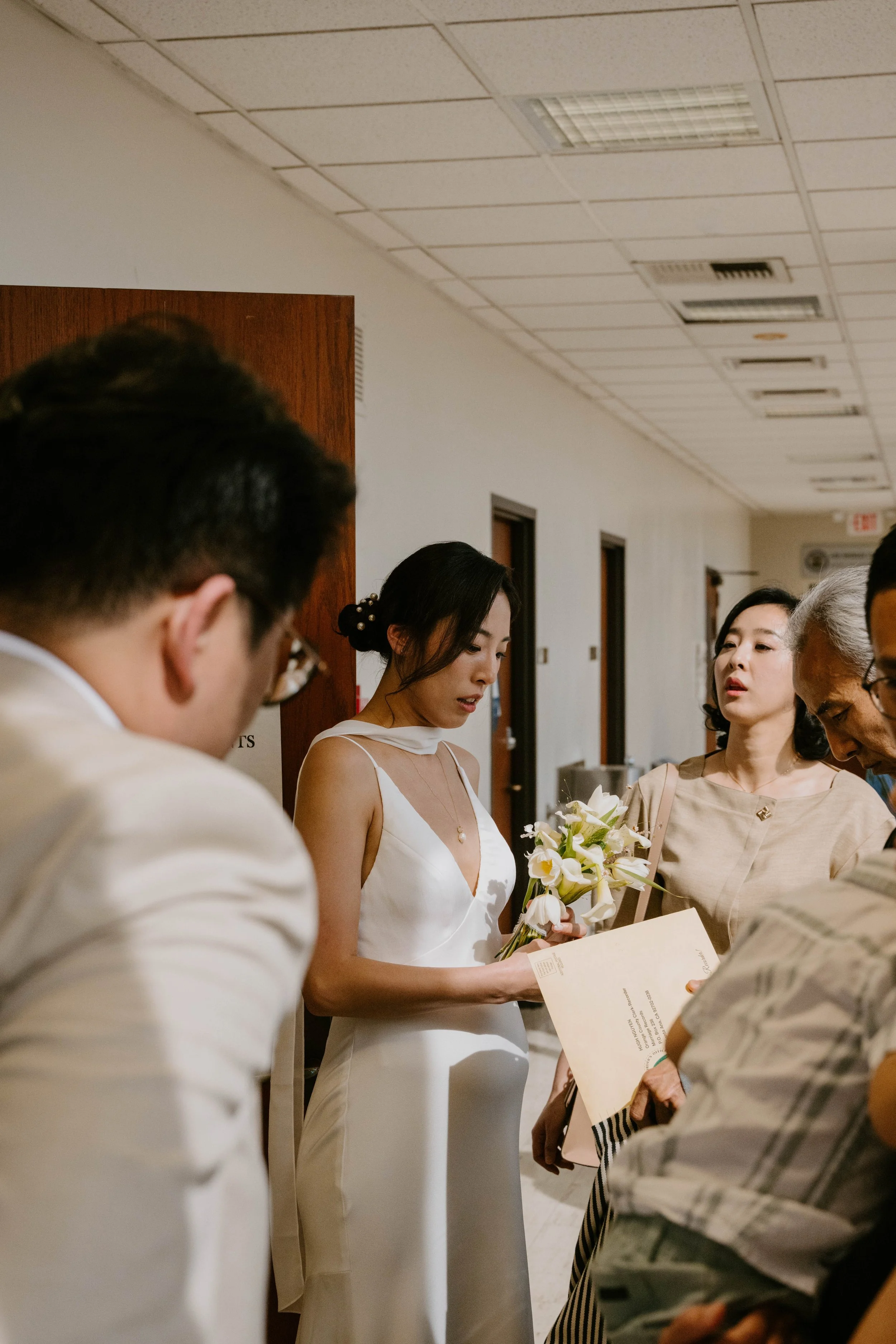Bride and groom standing with family in hallway waiting for courthouse ceremony