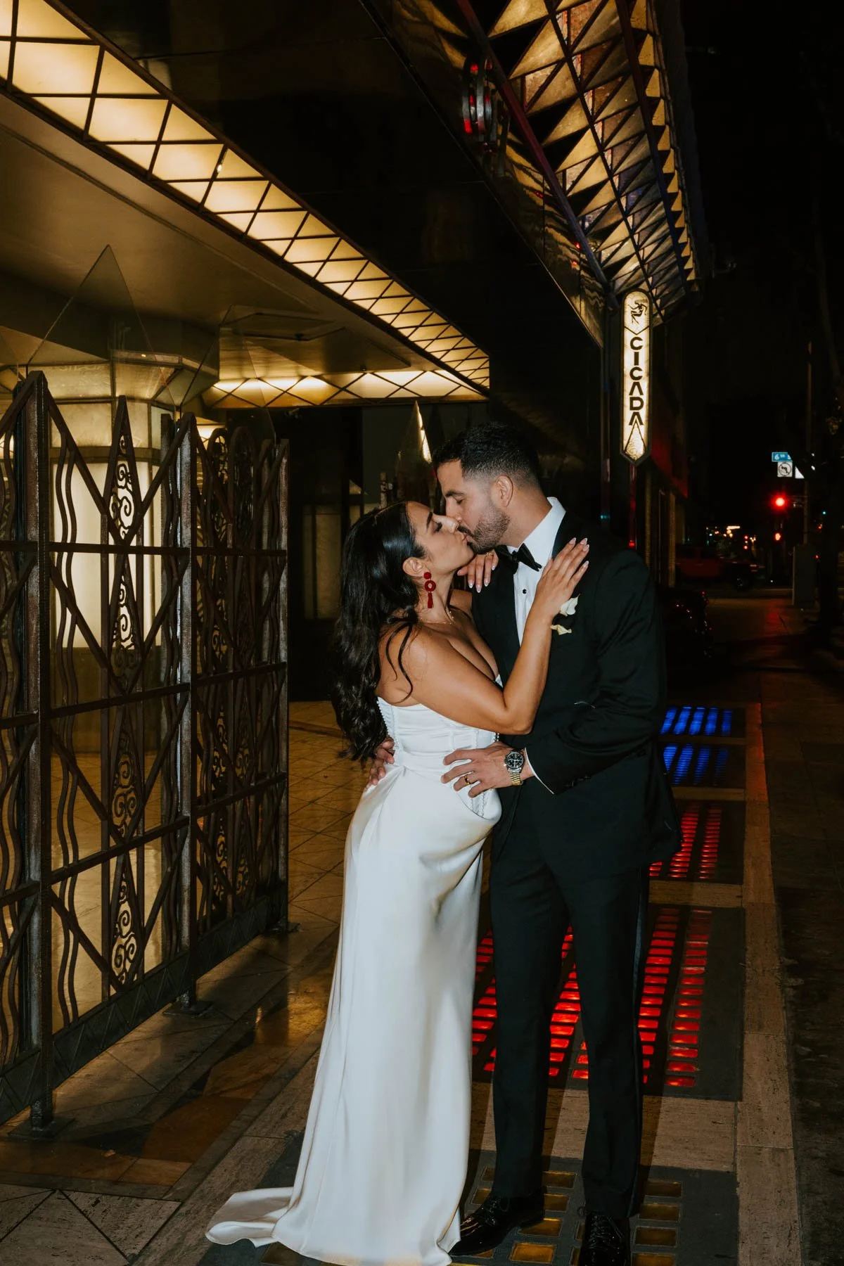 Bride and groom kissing on the sidewalk at night