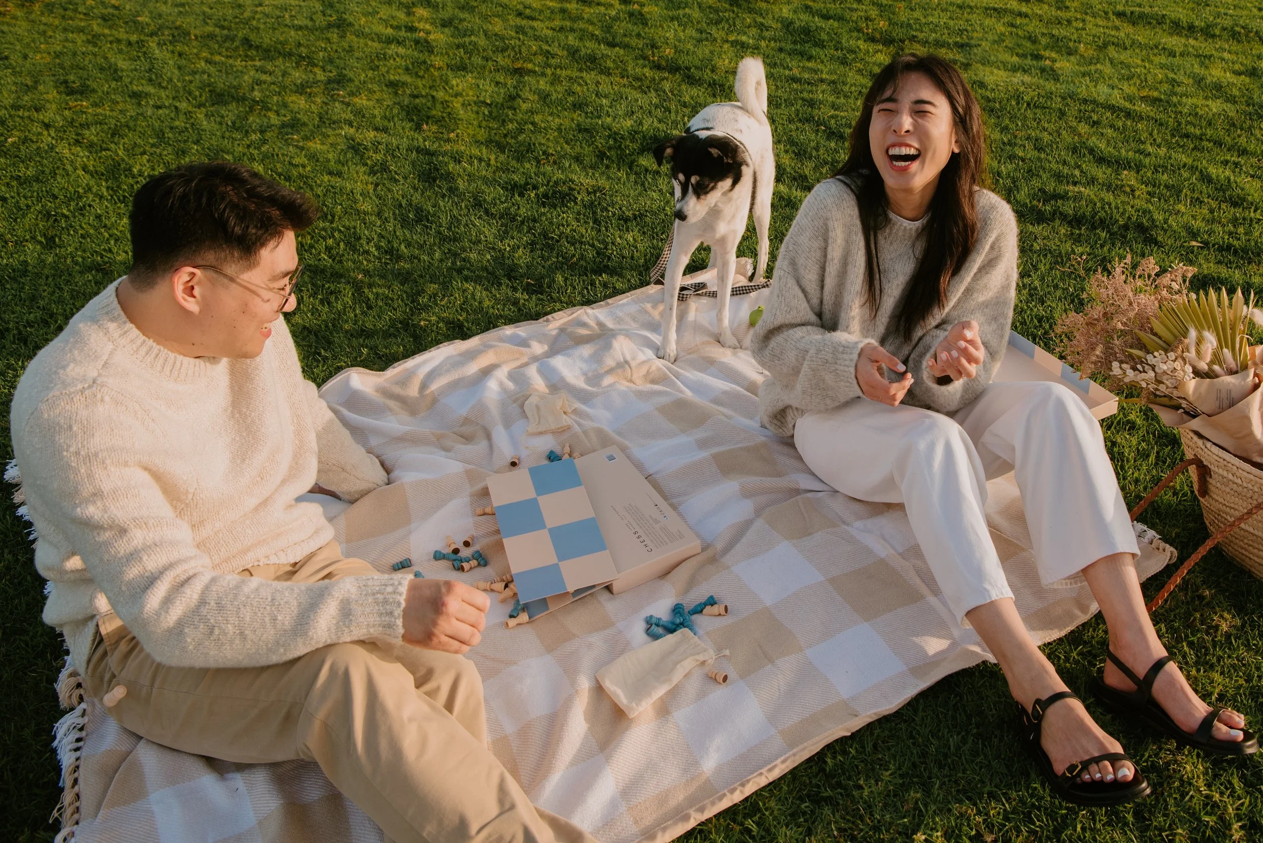 Couple laughing on a blanket as chess board is knocked over