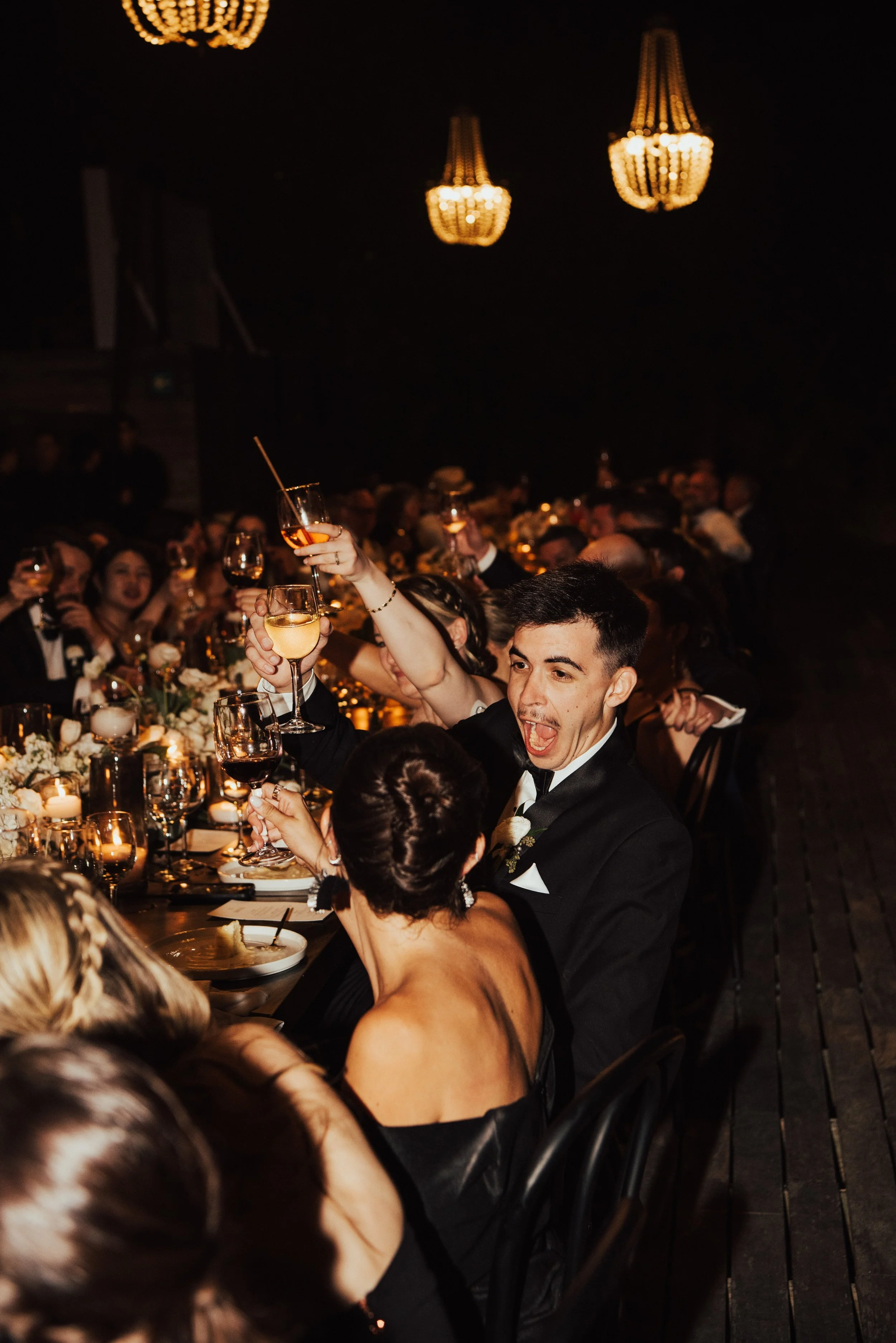 wedding guest excited as he raises his glass to the guest next to him