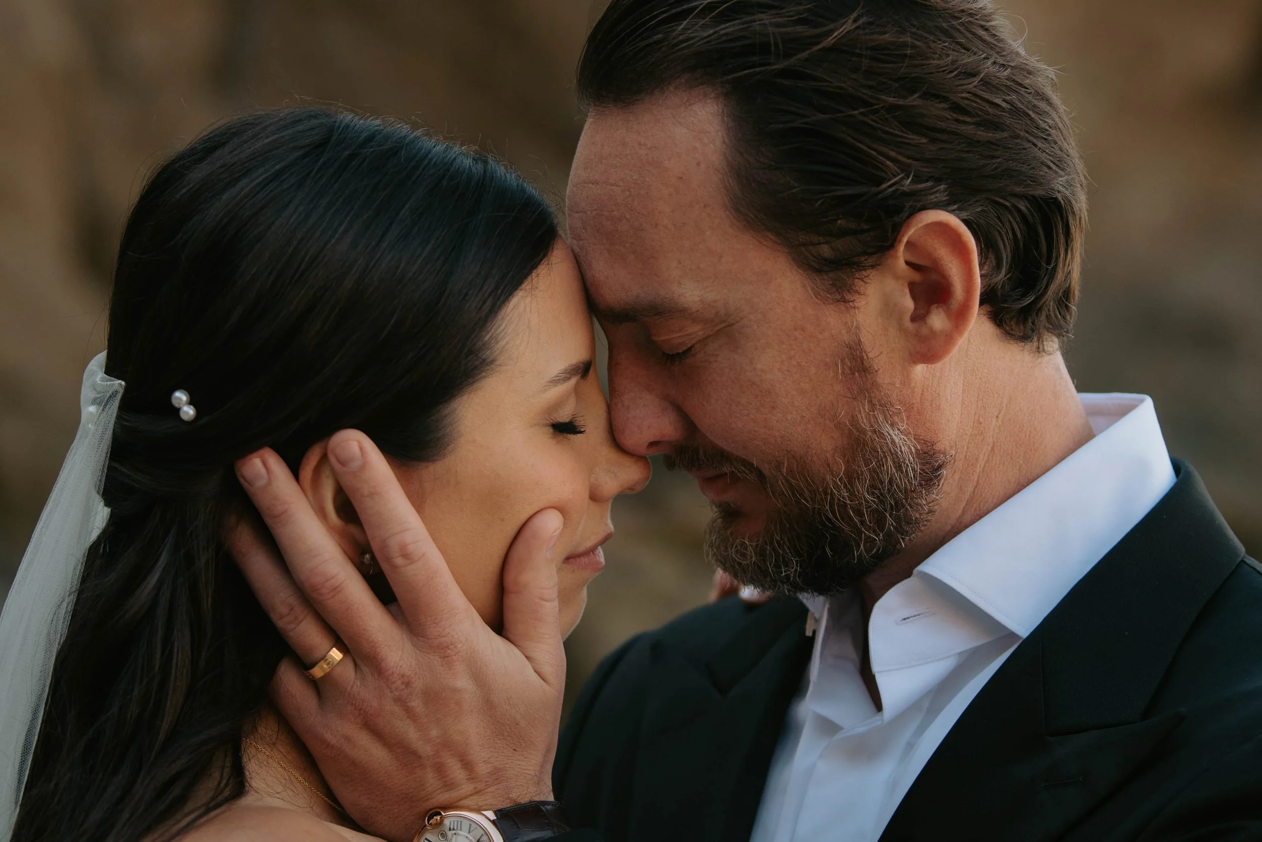 close up of bride and groom resting their foreheads together as groom holds brides face
