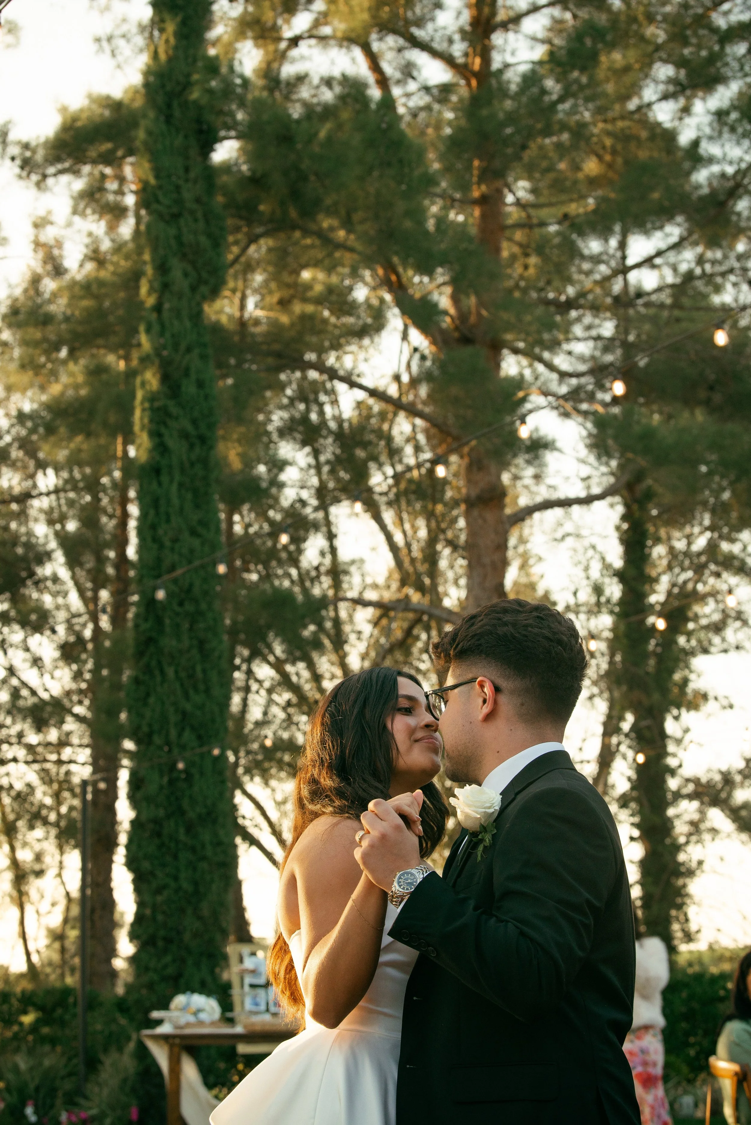 Shot of bride and grooms first dance. Shot over grooms shoulder and you can see bride looking at groom