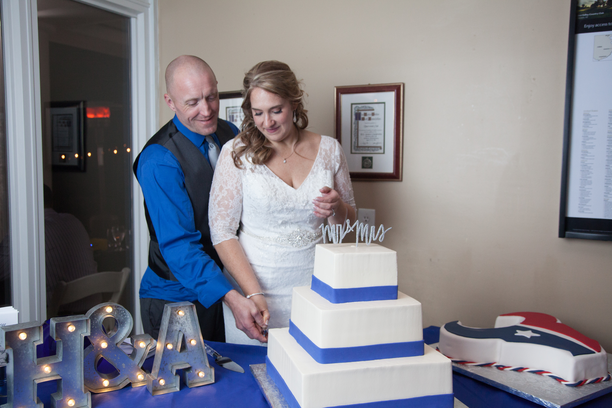 The couple cuts the white three tier wedding cake.