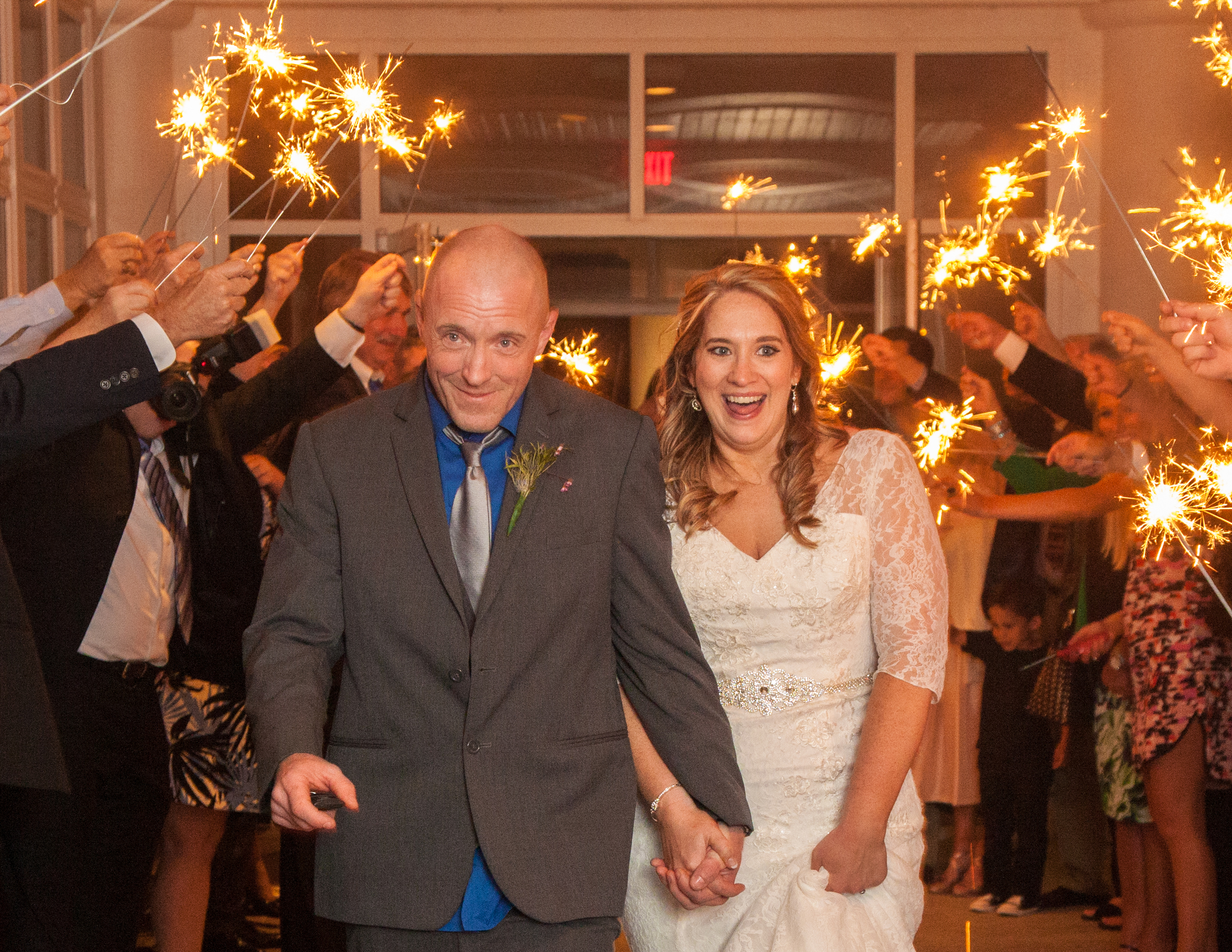 Husband and wife make their grand exit through a tunnel of sparklers leading to their getaway car.