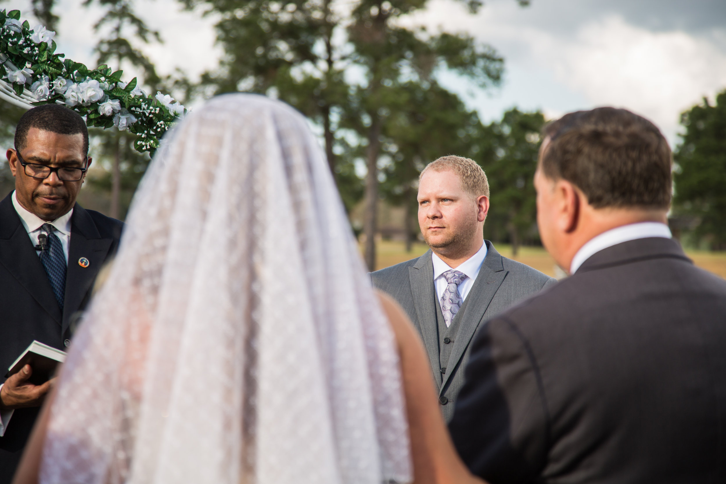 The groom Kennith looks on as bride Jessica stands with her father in wait before the minister asks him to give her away.