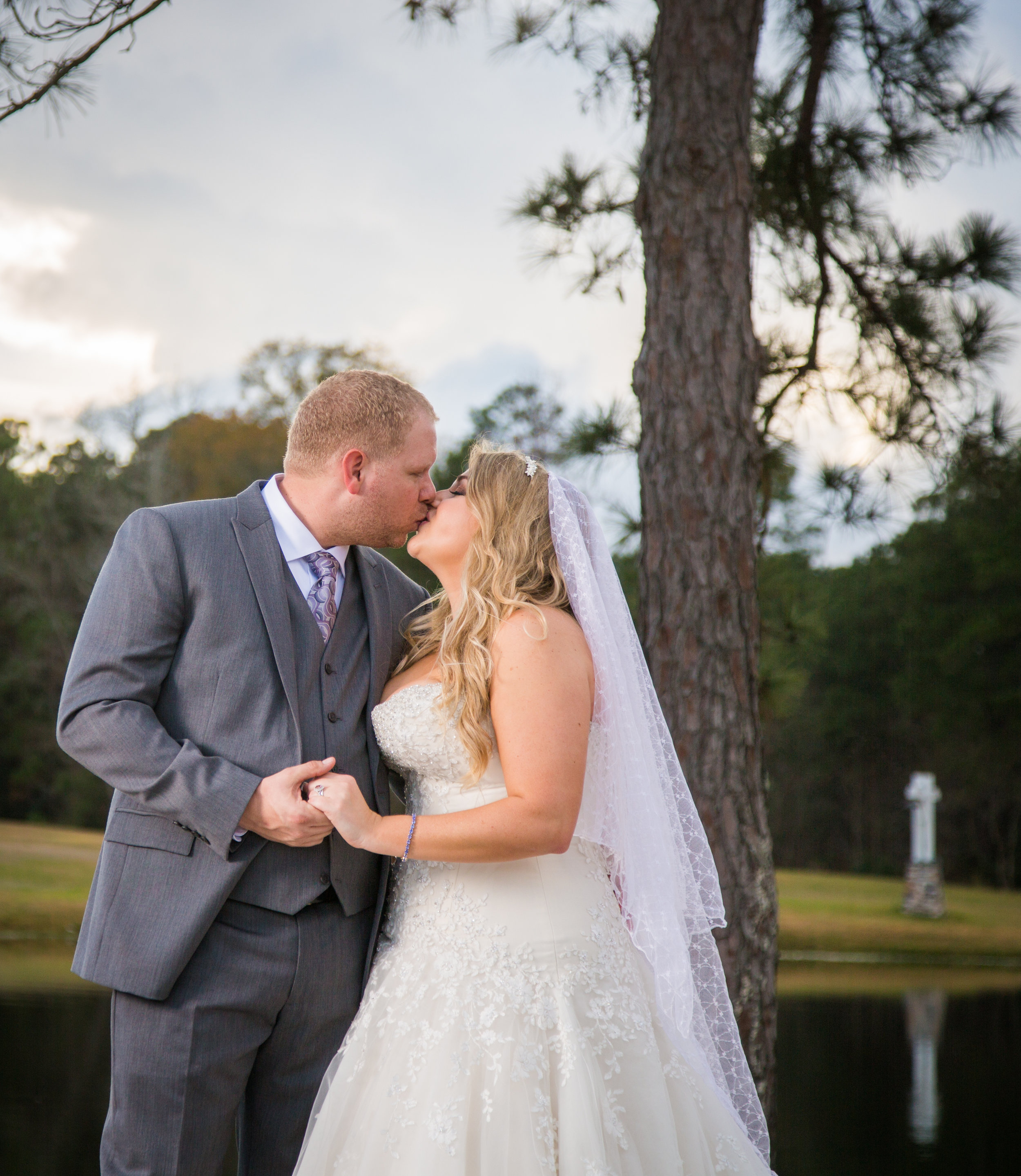 The married couple shares a kiss as the sun sets in the background after the wedding ceremony.