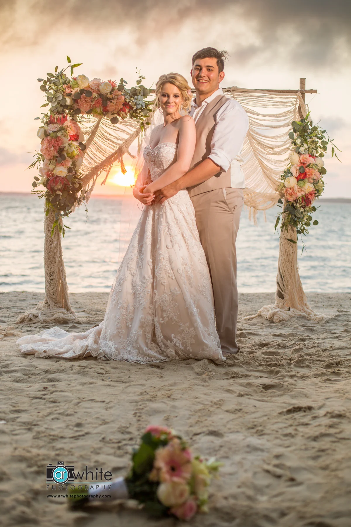 A young bride and groom pose for a photograph after their sunset wedding in Oc Maryland.