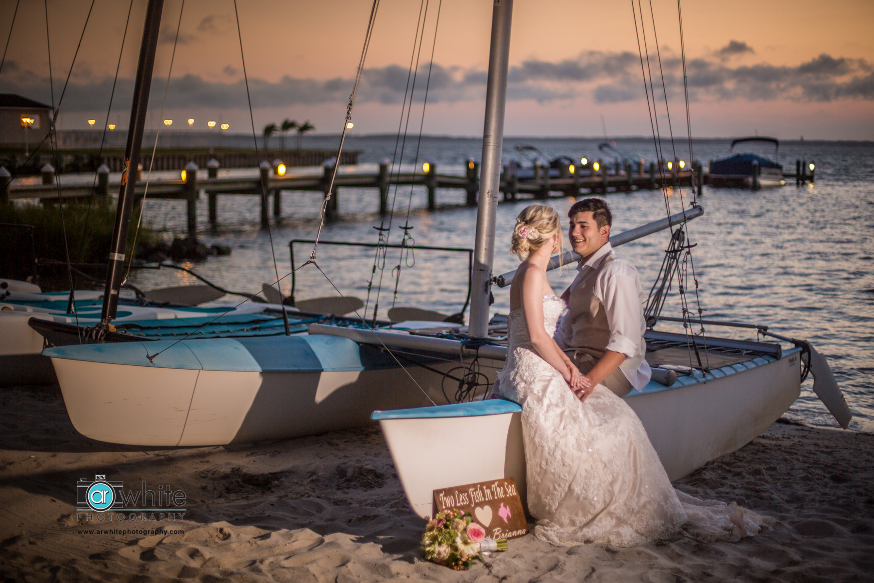 The newly married couple rest on a sailboat on the beach in Ocean City Maryland.