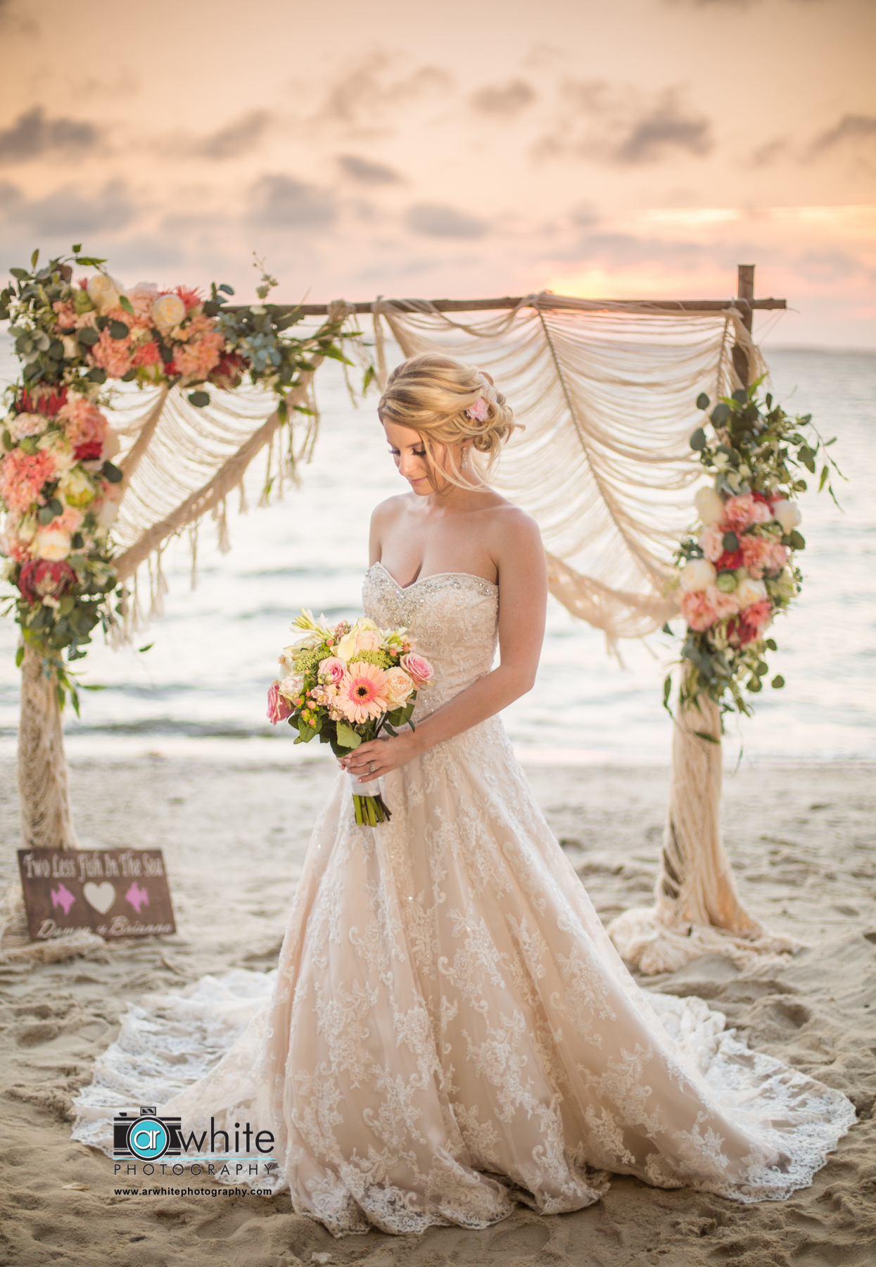 Brianna, bride holds her flower bouquet on the beach in front of the arbor after her Bohemian wedding in Oc Md.