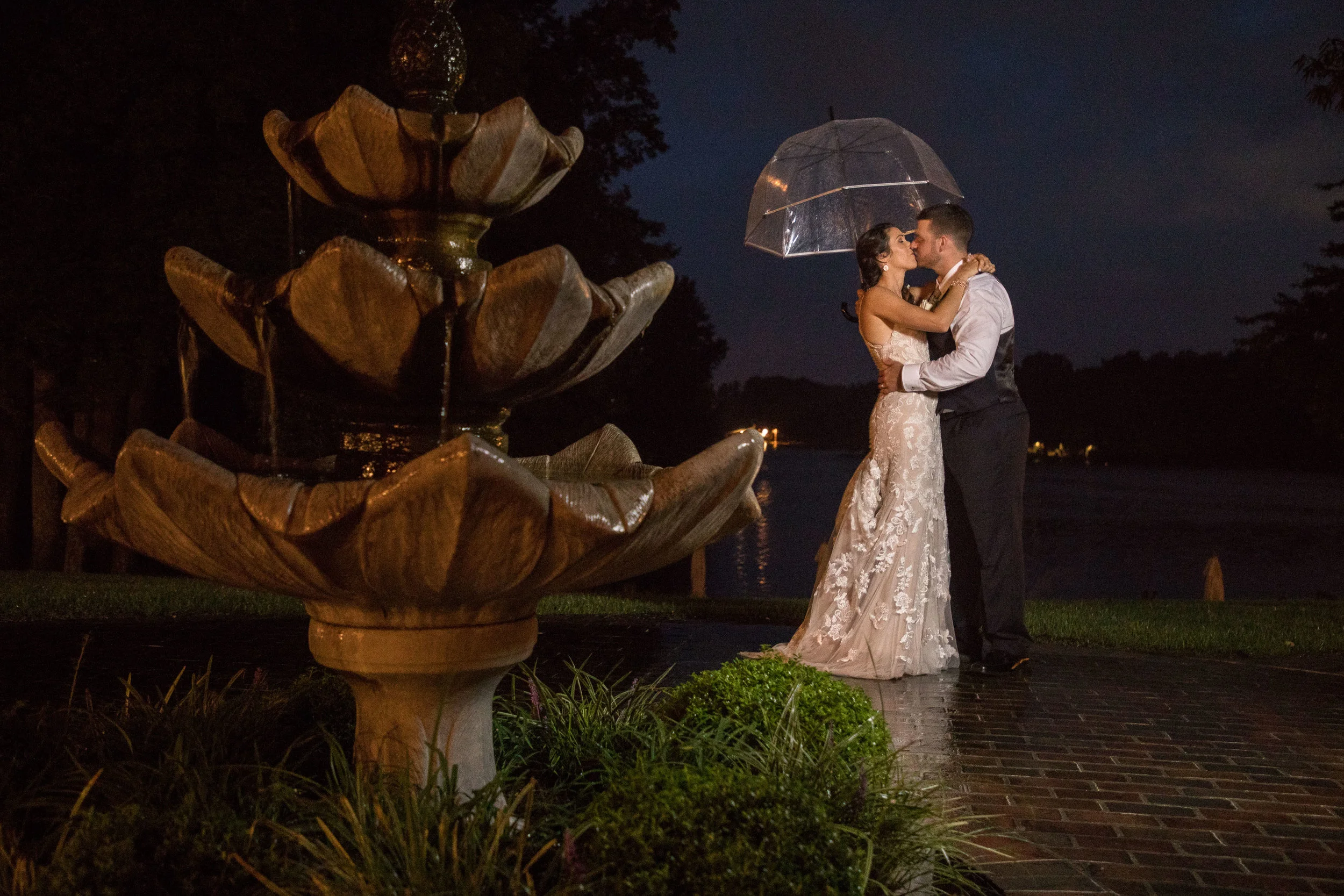 Carri and Jake share an umbrella and a kiss in the rain after the wedding ceremony.