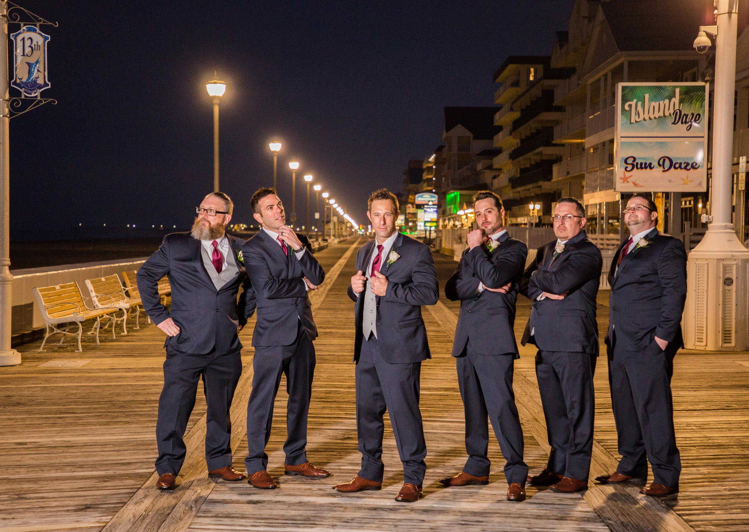 Groomsmen in their dark blue tuxedos and red ties pose on the boardwalk in Ocean City.