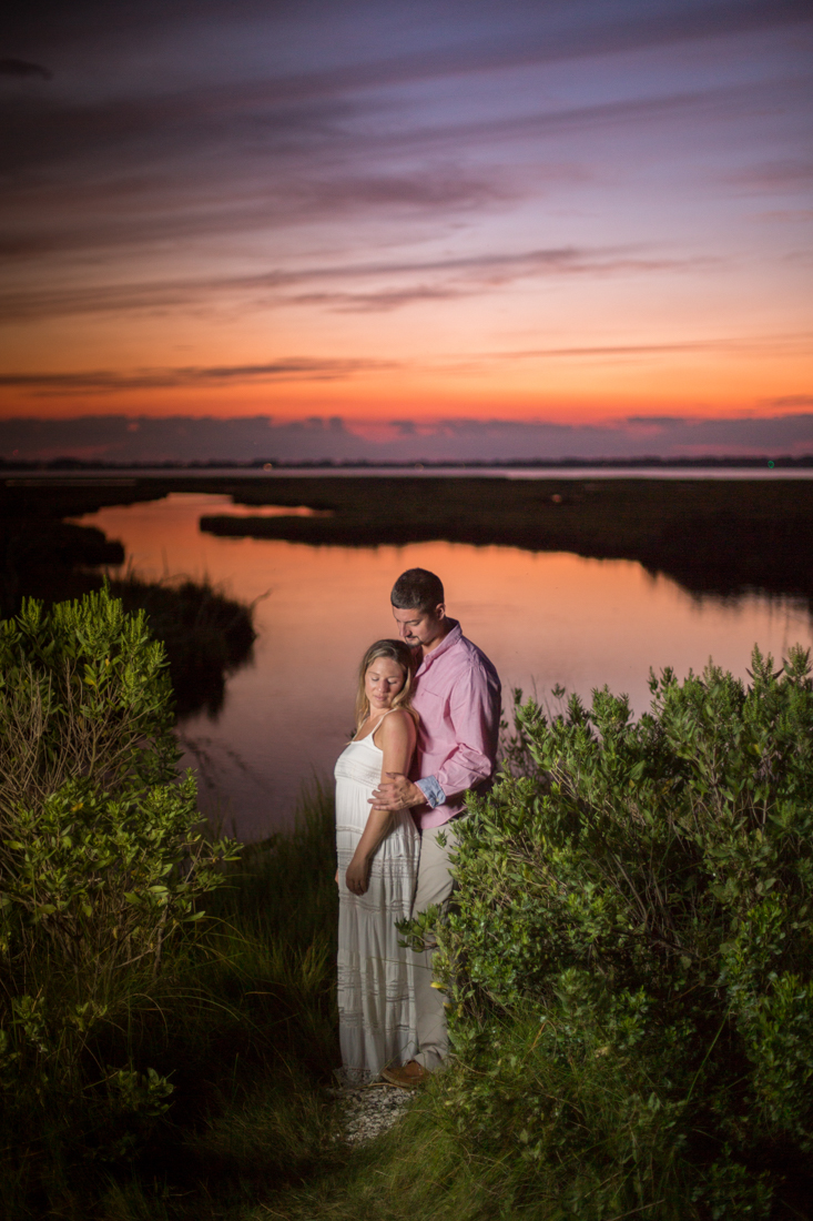 Engagement portrait of a man wearing a pink shirt with blue pants and his fiance wearing a white dress on the beach at Assateague taken by wedding photographers in Baltimore ARWhite Photography (Copy)