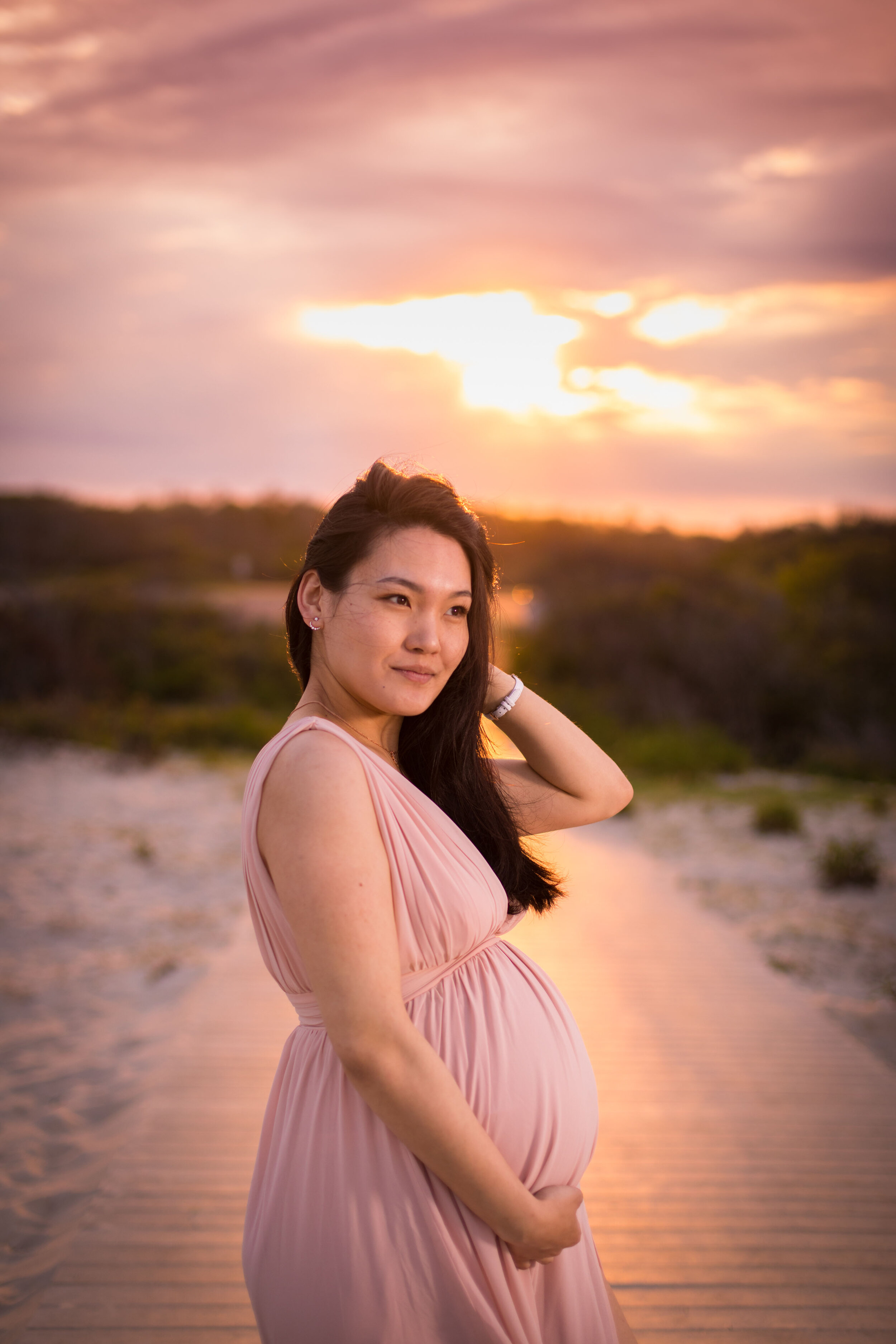 Photo of a pregnant woman in long flowy pink dress on the beaches of Assateague during her OCMD maternity session taken by photographers in Ocean City Maryland ARWhite Photography. (Copy)