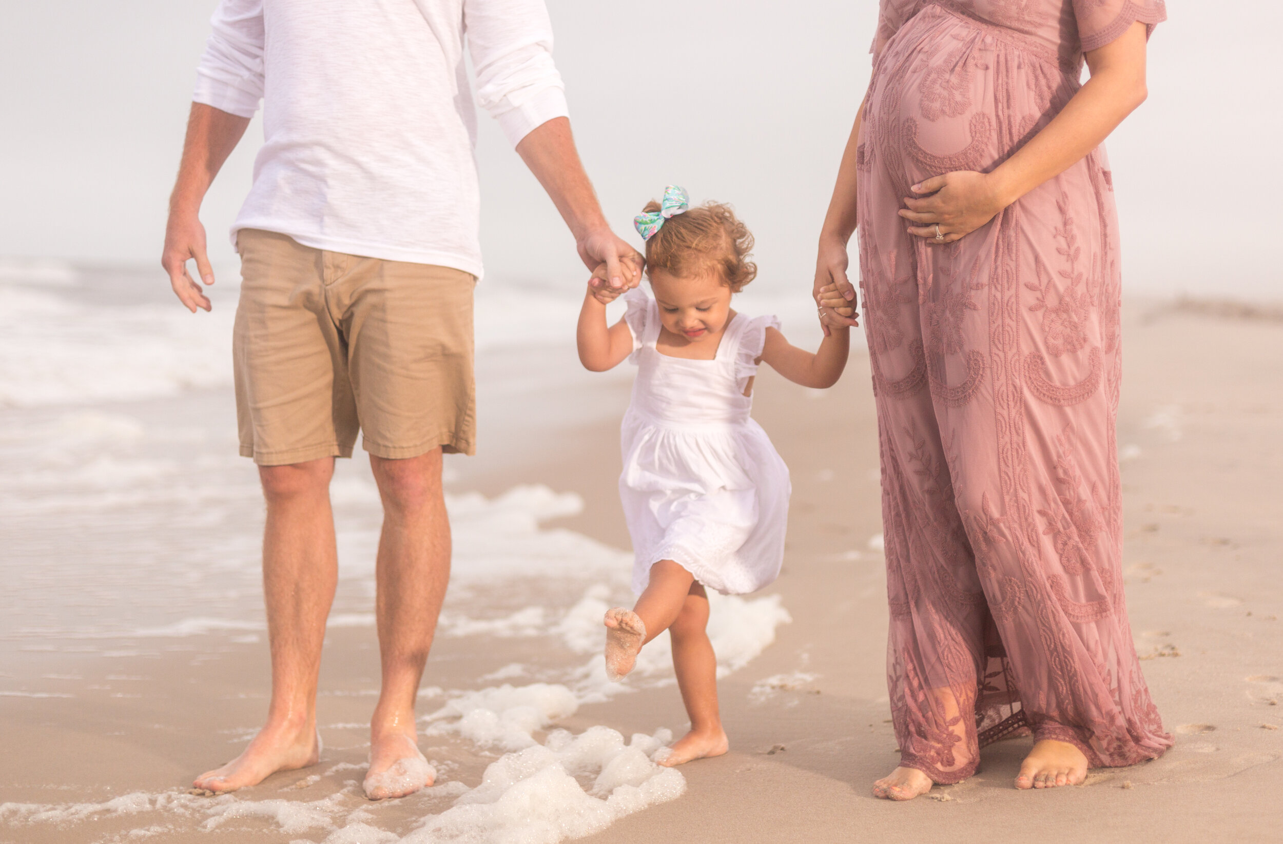Photo of a pregnant woman with her daughter and husband on the beaches of Assateague during her Ocean City Maryland session taken by photographers in OCMD ARWhite Photography. (Copy)