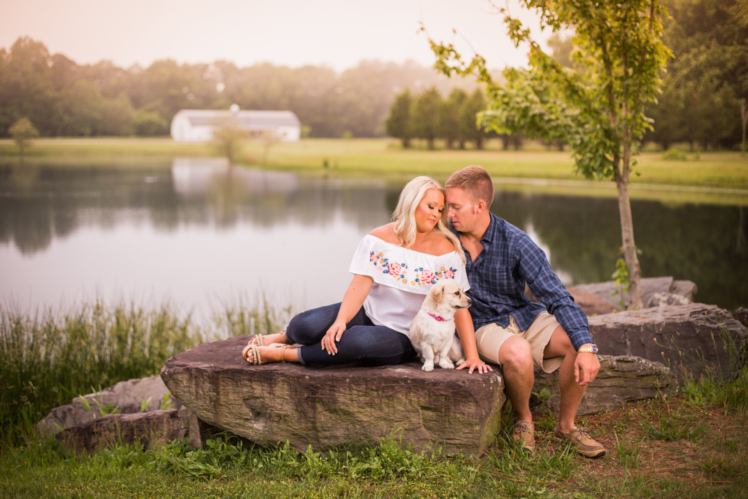 Photo of a young couple sitting on a rock next to a lake during their engagement session at Smokey Hollow wedding venue in Delaware taken by wedding photographers in Baltimore ARWhite Photograp (Copy)