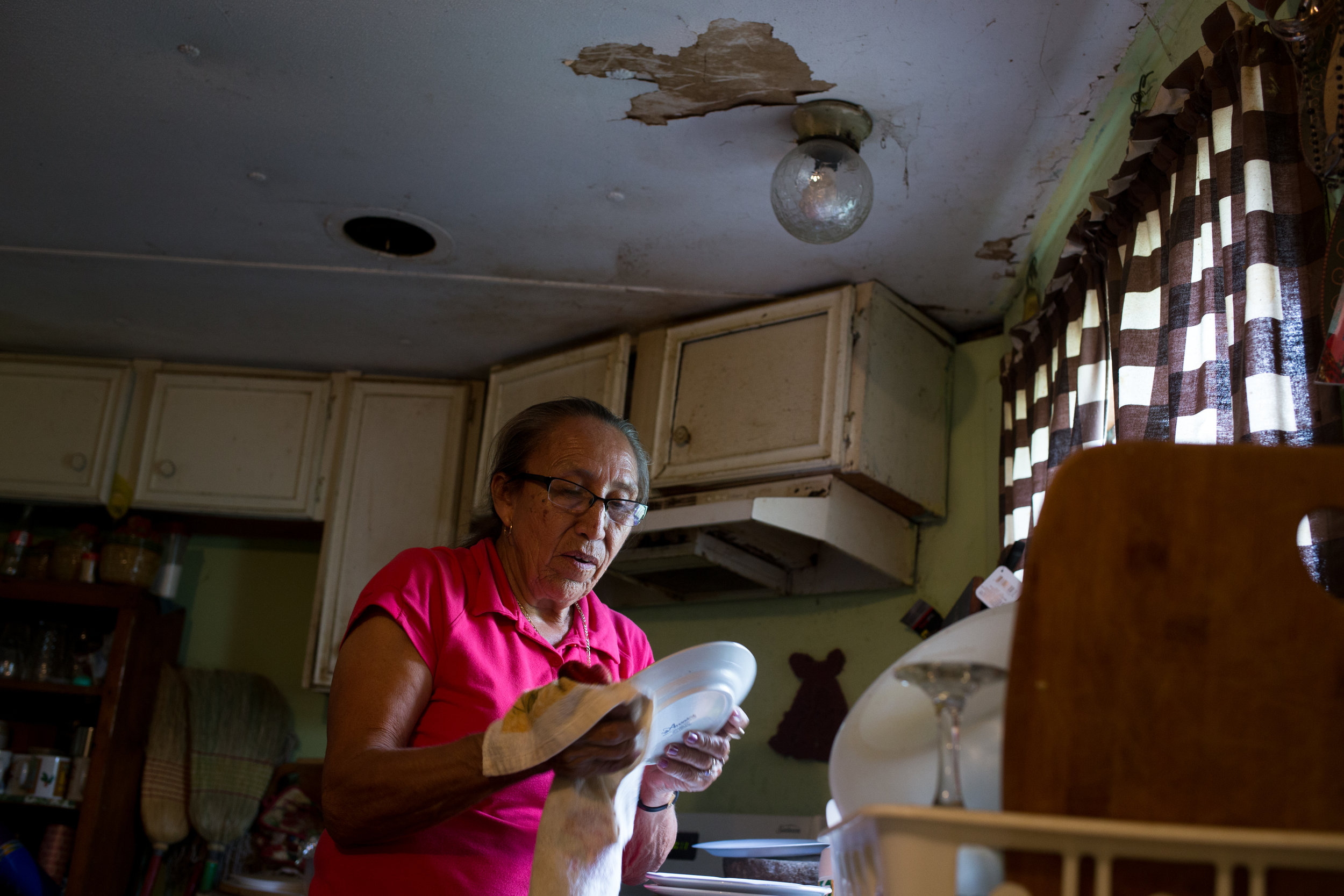  Teresa washes dishes after feeding her grandchildren lunch. Heavy rains and floods each year have damaged the ceiling, foundation and floors of the mobile home Teresa bought 18 years ago for $8000. She said she wouldn’t be able to afford monthly pay