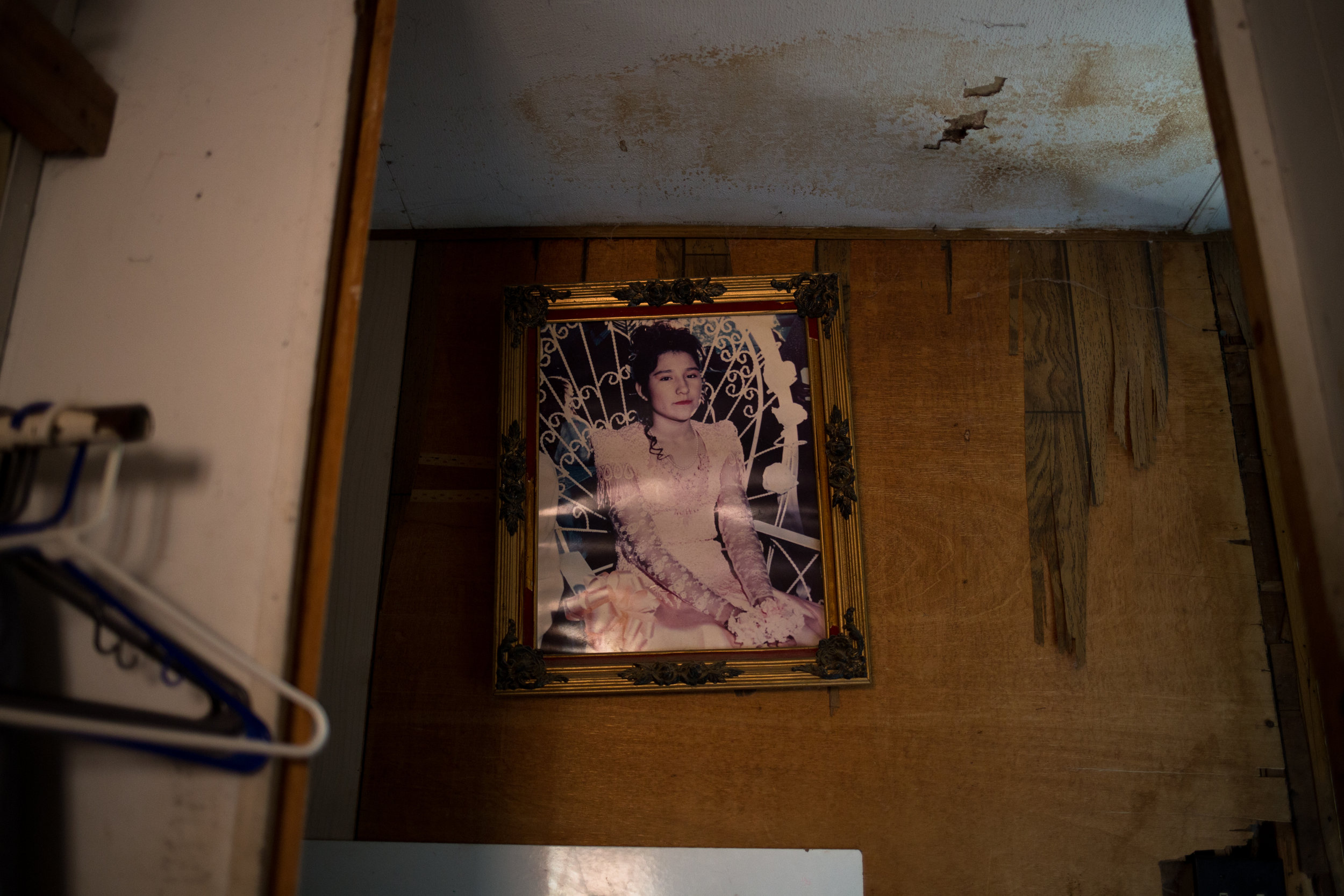  A photograph of Teresa’s daughter hangs in a visibly water-damaged hallway. 