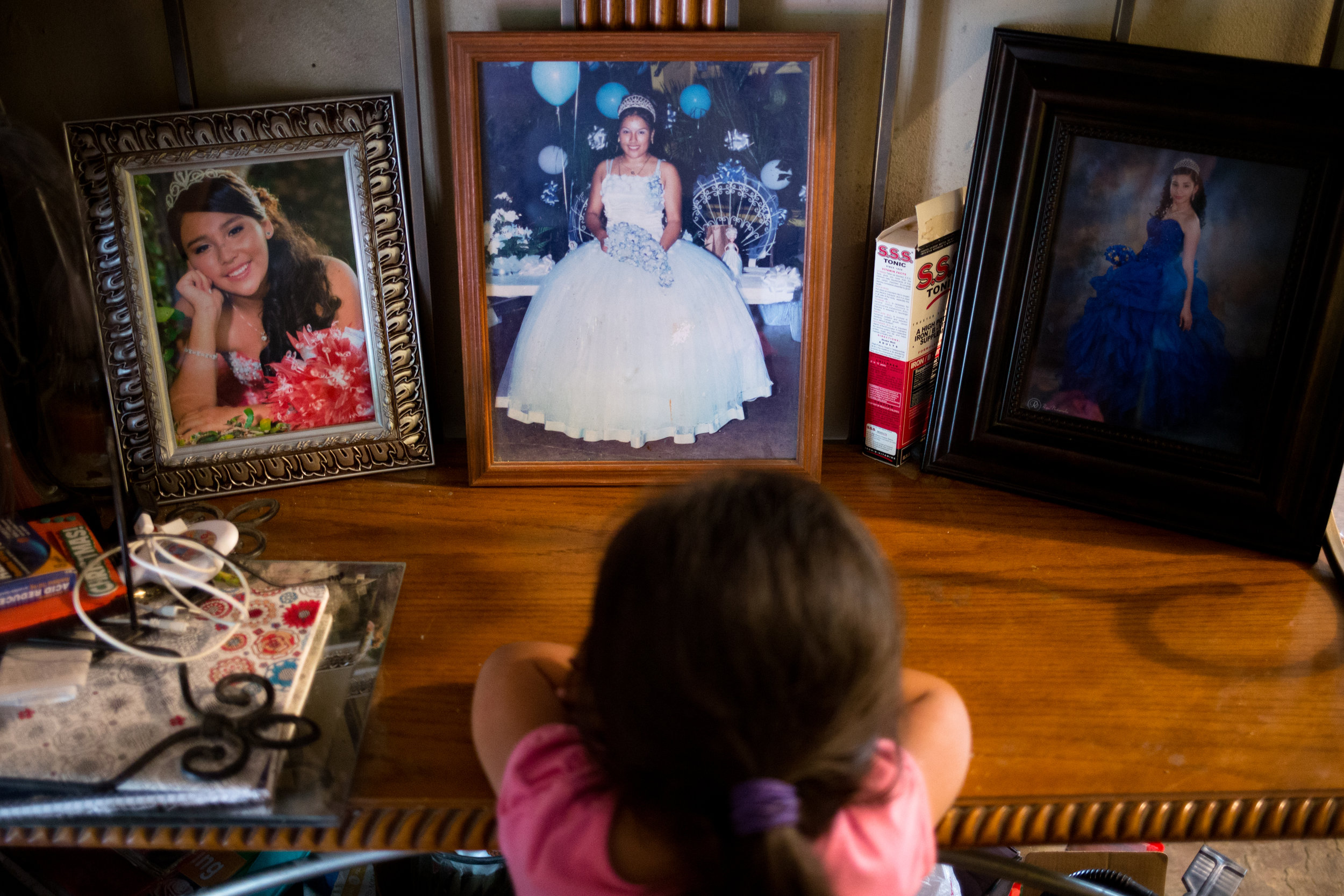  Ashlee, 4, looks at photos of her mother and other female relatives at their quinceañeras, a fifteenth&nbsp;birthday celebration commonly celebrated among Mexicans and Mexican-Americans along the border. Ashlee's mother works&nbsp;as a full-time med