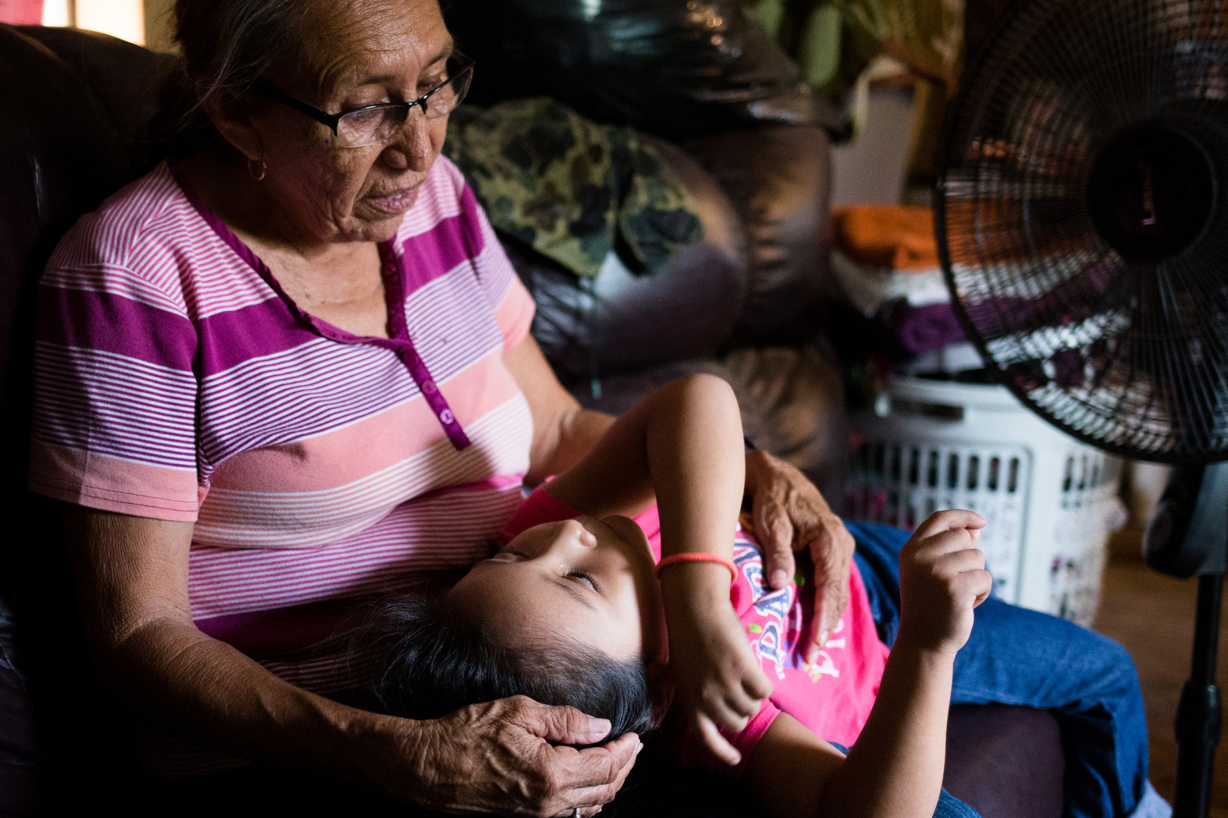  Teresa and her grandchild, Ashlee, rest for a moment by one of three fans used to keep the heat at bay in their poorly insulated mobile home. Teresa quit her job as a home care provider to care for her children, but she and her adult daughter strugg