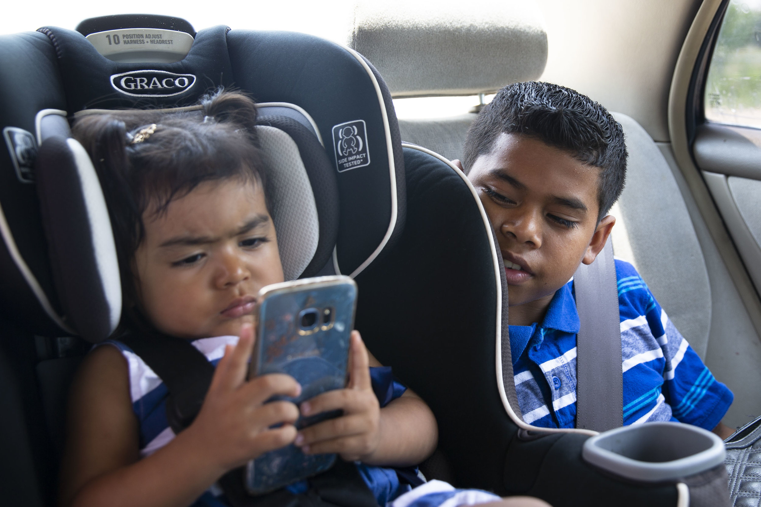  David Rosales, 11, watches his 2-year-old sister, Kelly, play with his mother's phone as they drive to a doctor's appointment on Friday, June 22, 2018. 