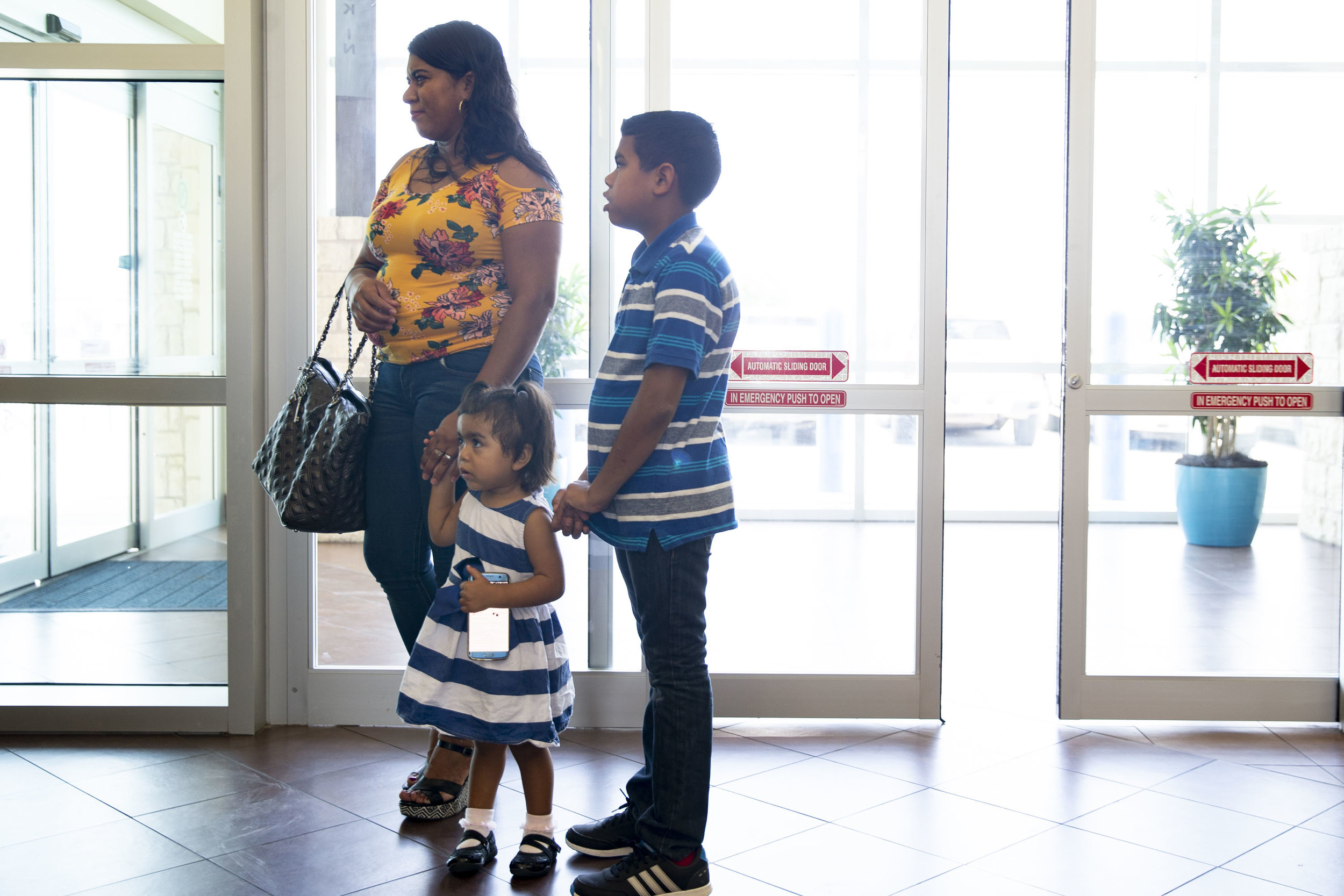  Lizeth Rosales, an asylum recipient from Honduras, stands in a health facility with her two children, David, 11, and Kelly, 2, in Kyle, Texas, on Friday, June 22, 2018. 
