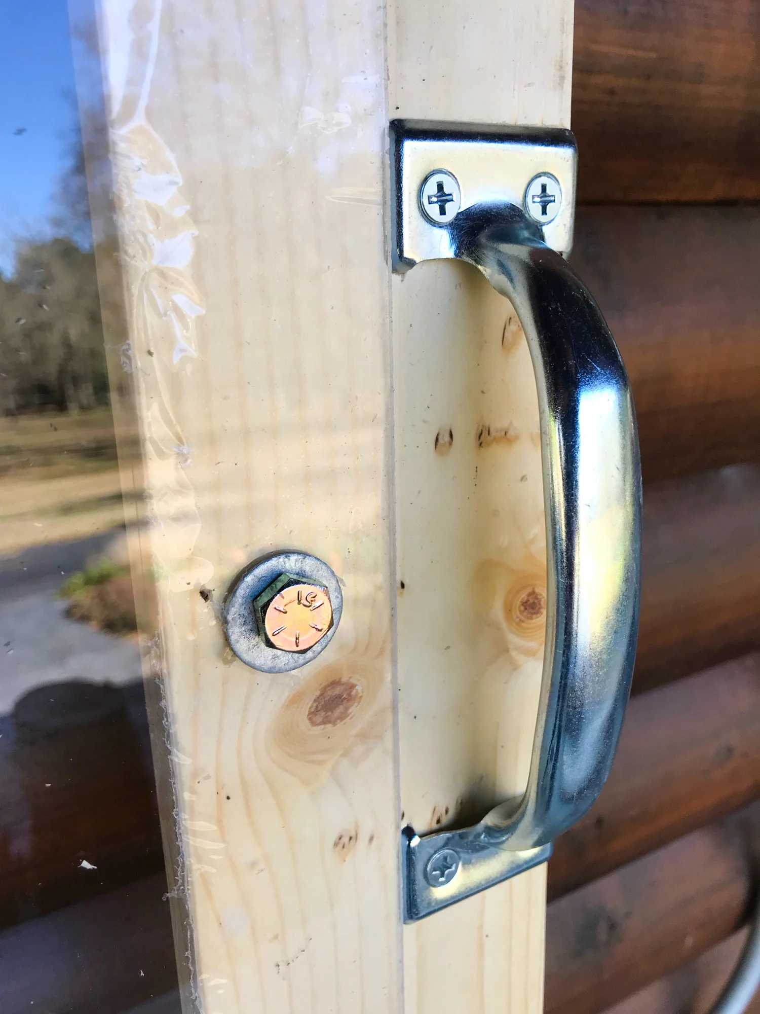 A bolt and washer hold the plexiglass on the wooden frame, and to the right is a handle for the light.