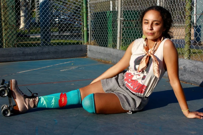 Skating is Slic Vic’s life; the adrenaline and freedom to explore with skates is essential for her. Roller skating fashion is a collaboration of body motion and tricks with whatever you’re wearing. On skates, she loves dressing extravagantly and with lots of bright colors. The way she would describe how she dresses on skates is something she’d wear to a party—almost as a more feminine alter ego of herself. She’s pictured wearing a “clash of cultures” with an ’80s vibe—from her David Bowie shirt to her handkerchief and colorful high socks.