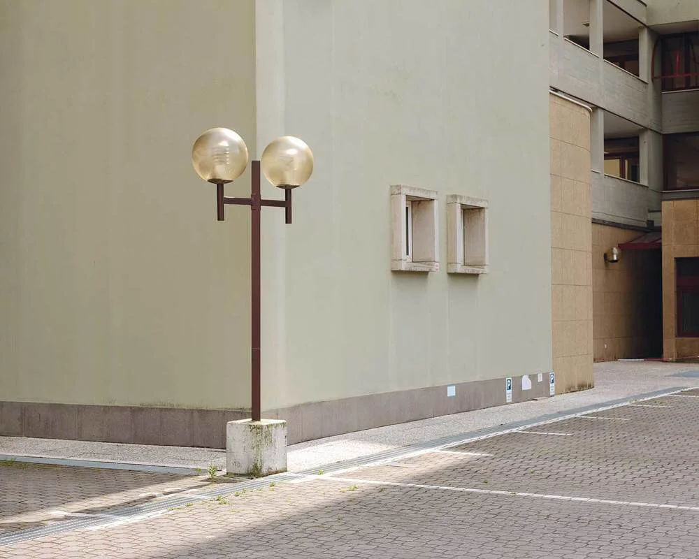 A streetlamp with two spherical lights near a building with two small square windows