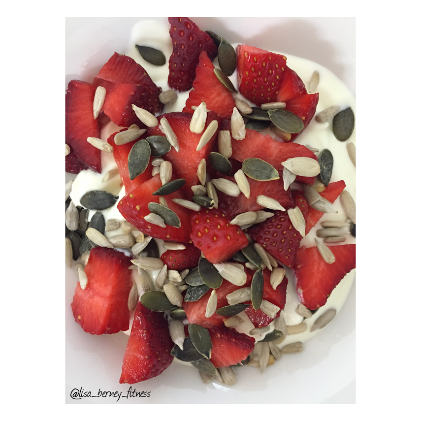 Yoghurt topped with strawberries, pumpkin and sunflower seeds.