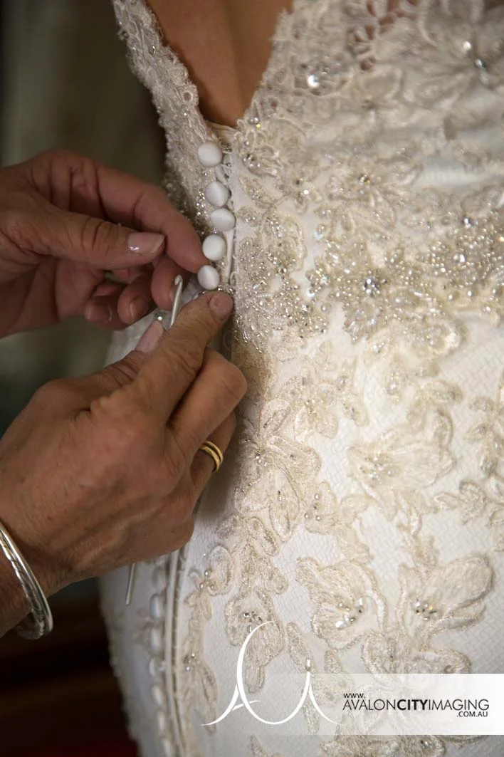 Detail photograph showing buttoning up wedding gown