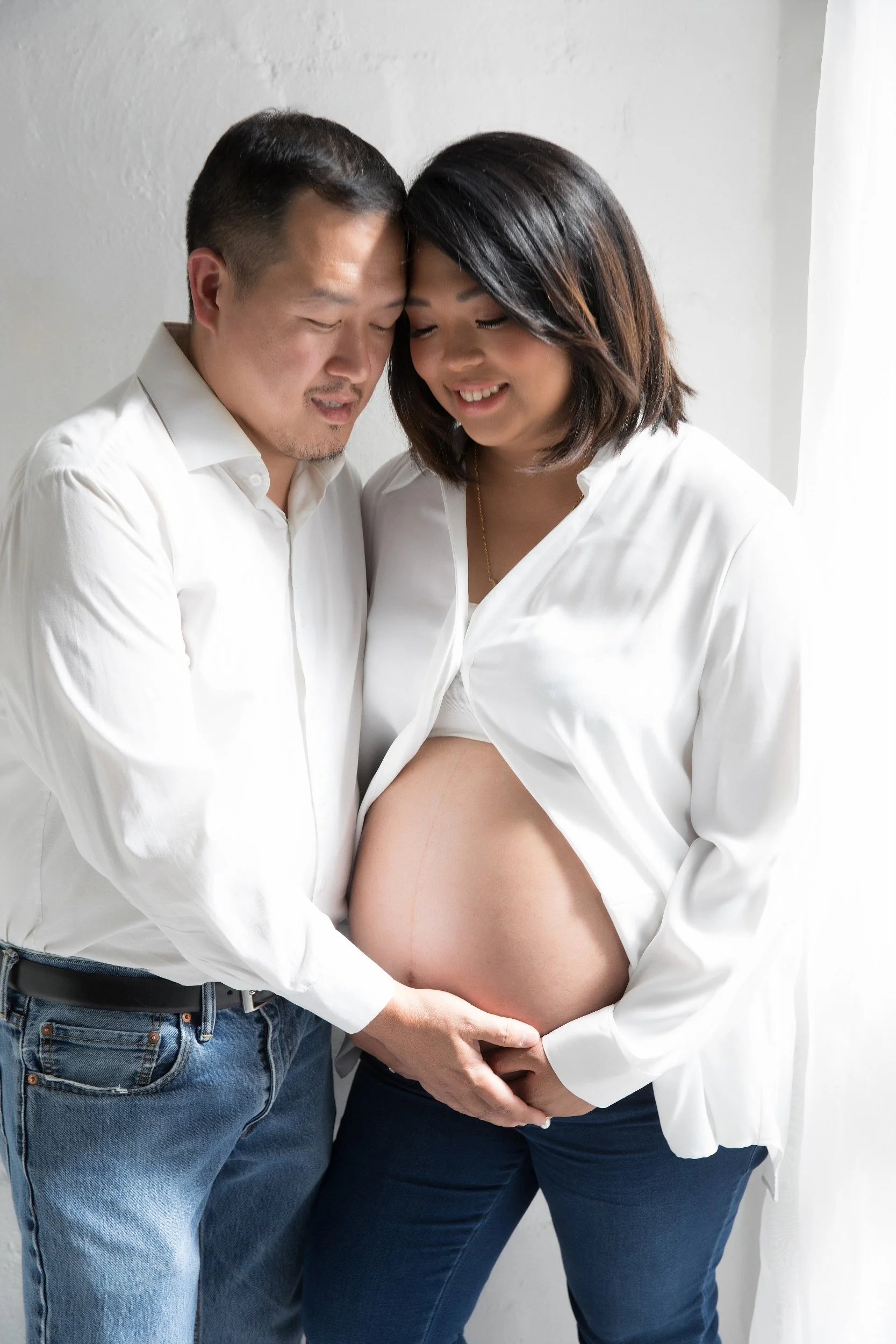 maternity photography - expecting parents holding the baby bump together in soft, glowing light.jpg