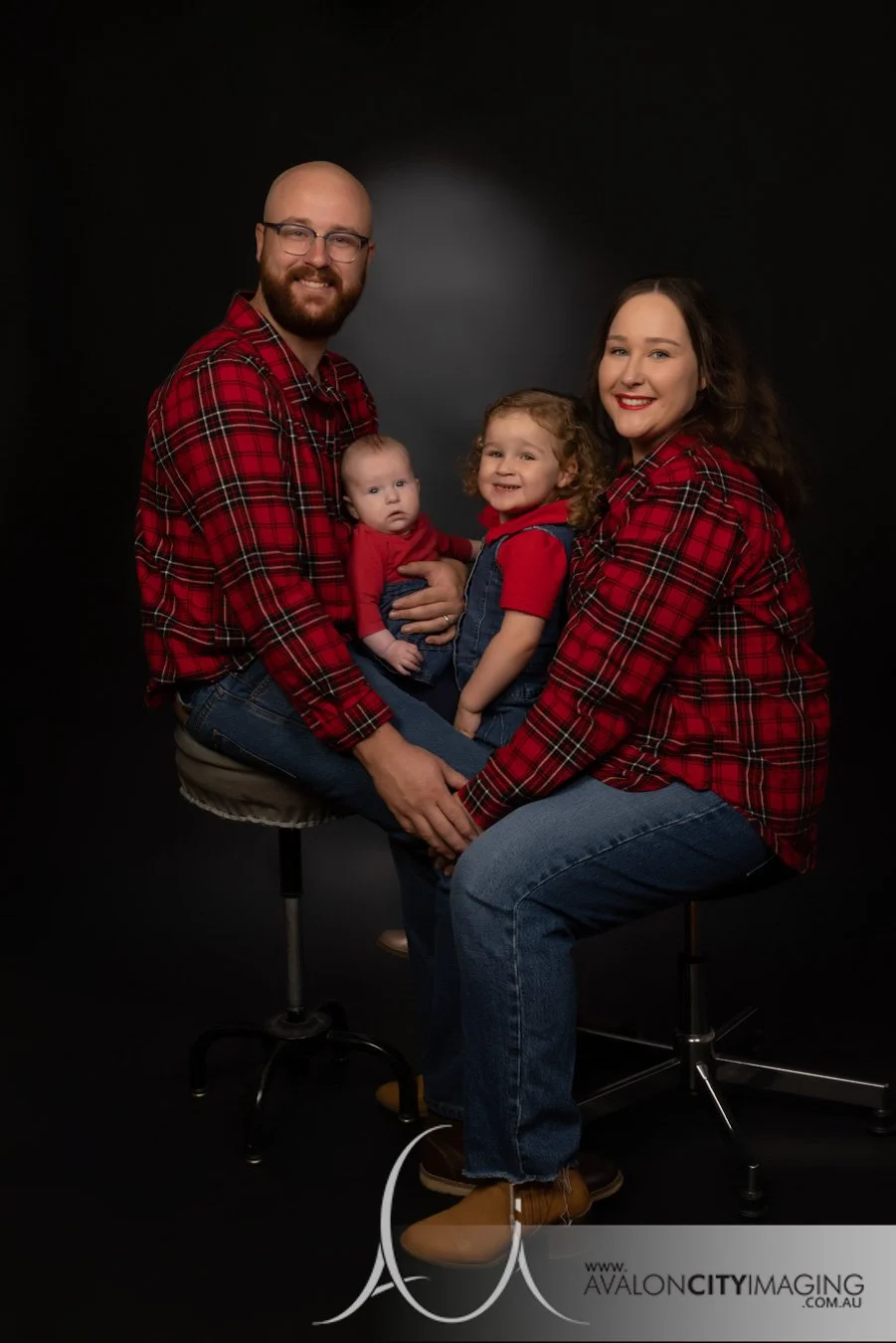 Family photography- family in matching outfit sitting together with plain studio backdrop awkward family photos.jpg
