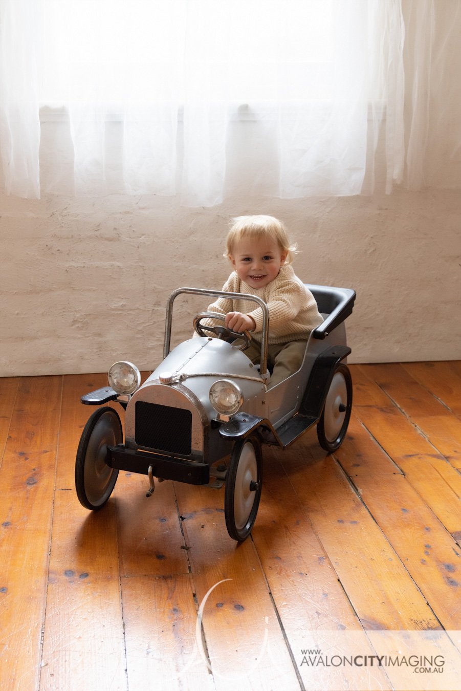 Family photography- child playing in a toy car smiling happily in studio cutest kidz.jpg