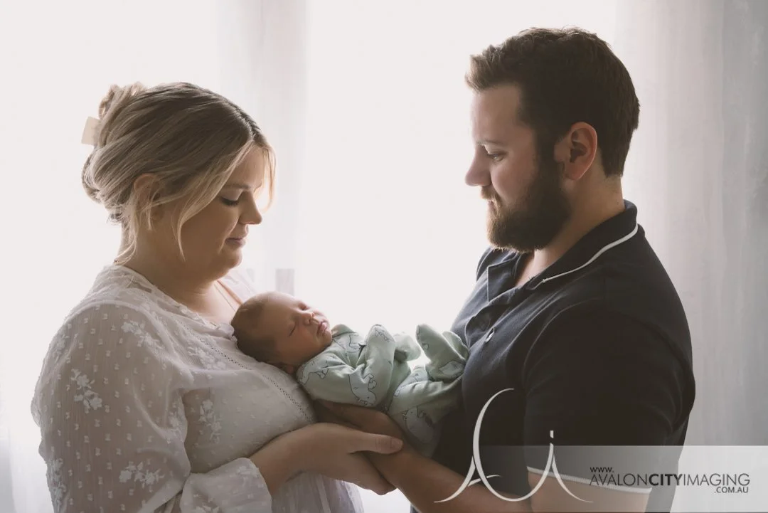 newborn photography - newborn held gently by both parents in a warm, connected pose.jpg