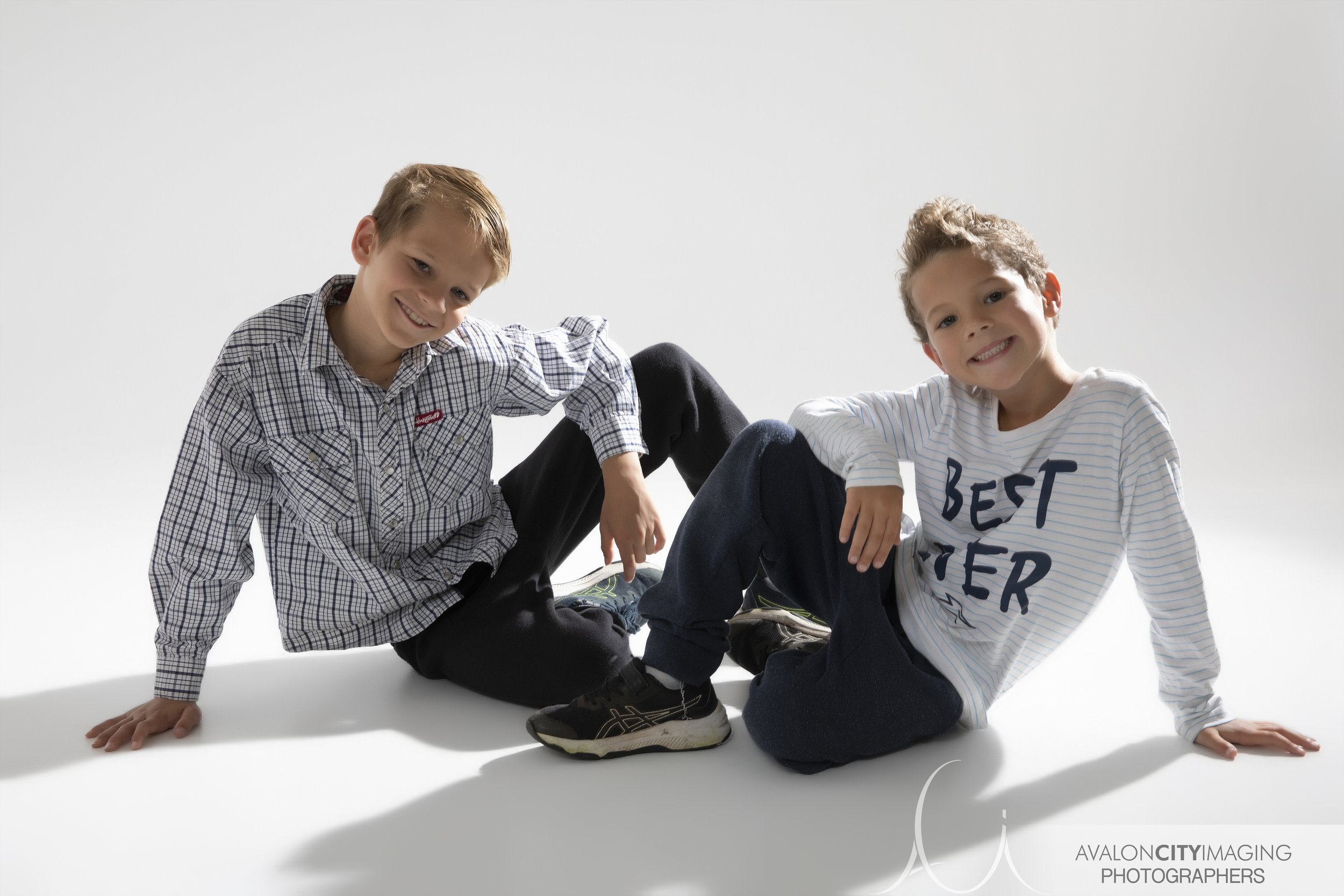 Family photography- brothers posed together smiling with bold shadowy studio lighting.jpg
