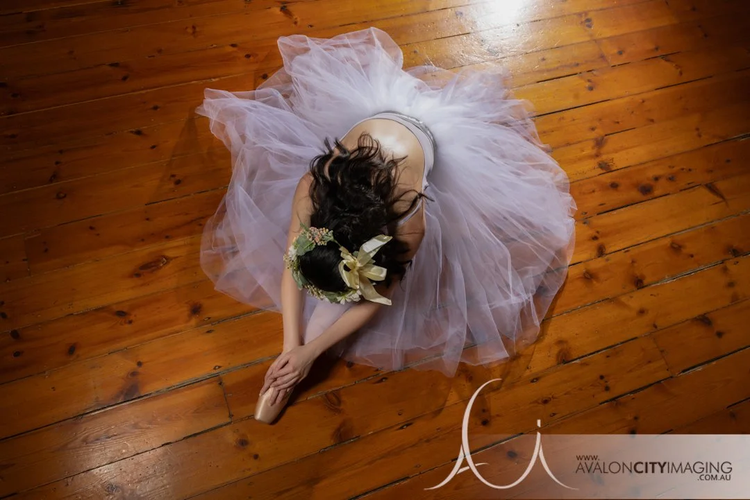 Dance photography- Elegant ballet pose in studio setting with strong lighting in pointe shoes